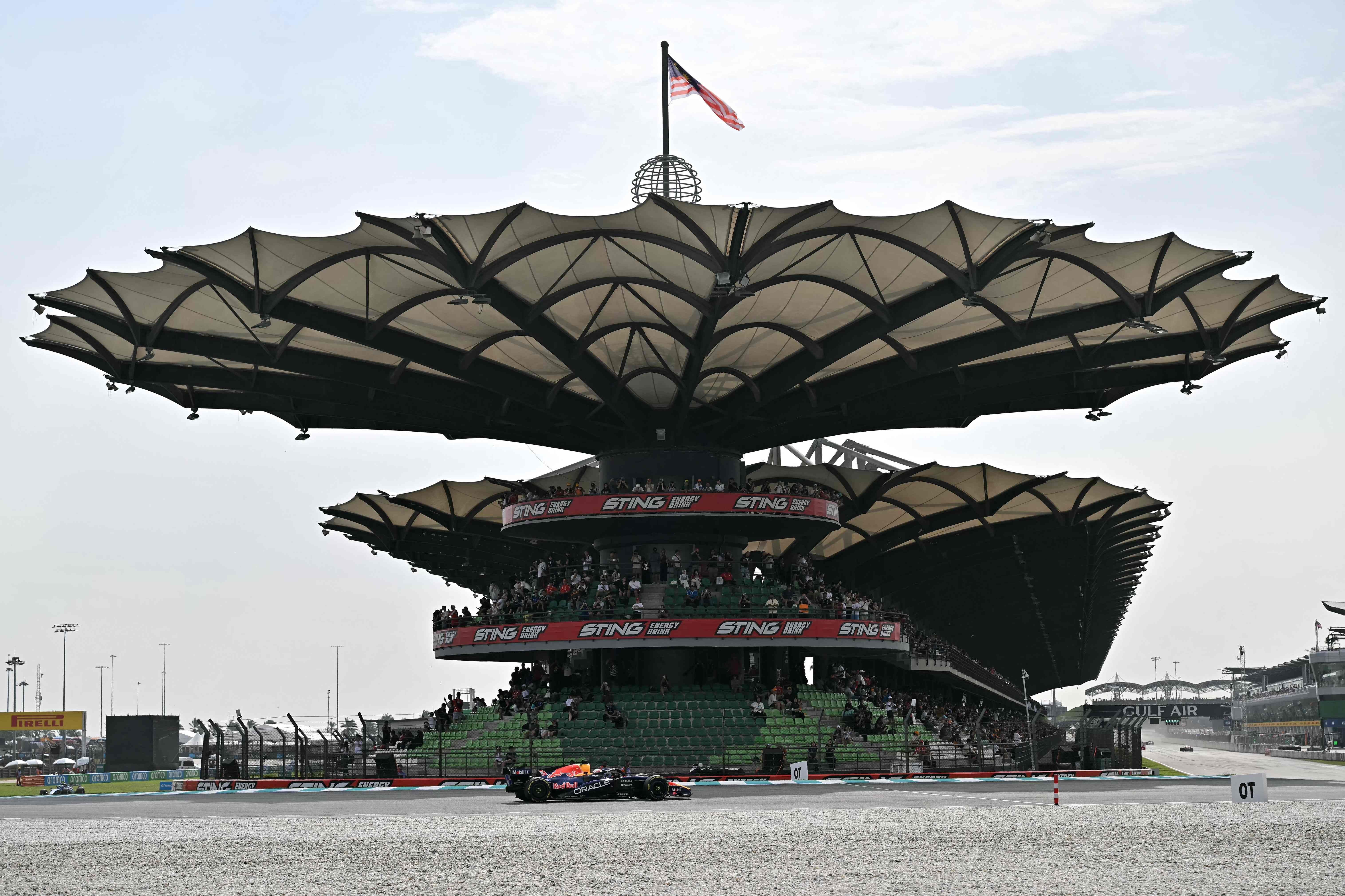 Ein Red Bull Formel-1-Rennwagen fährt vor der großen Tribüne des Sepang International Circuit.
