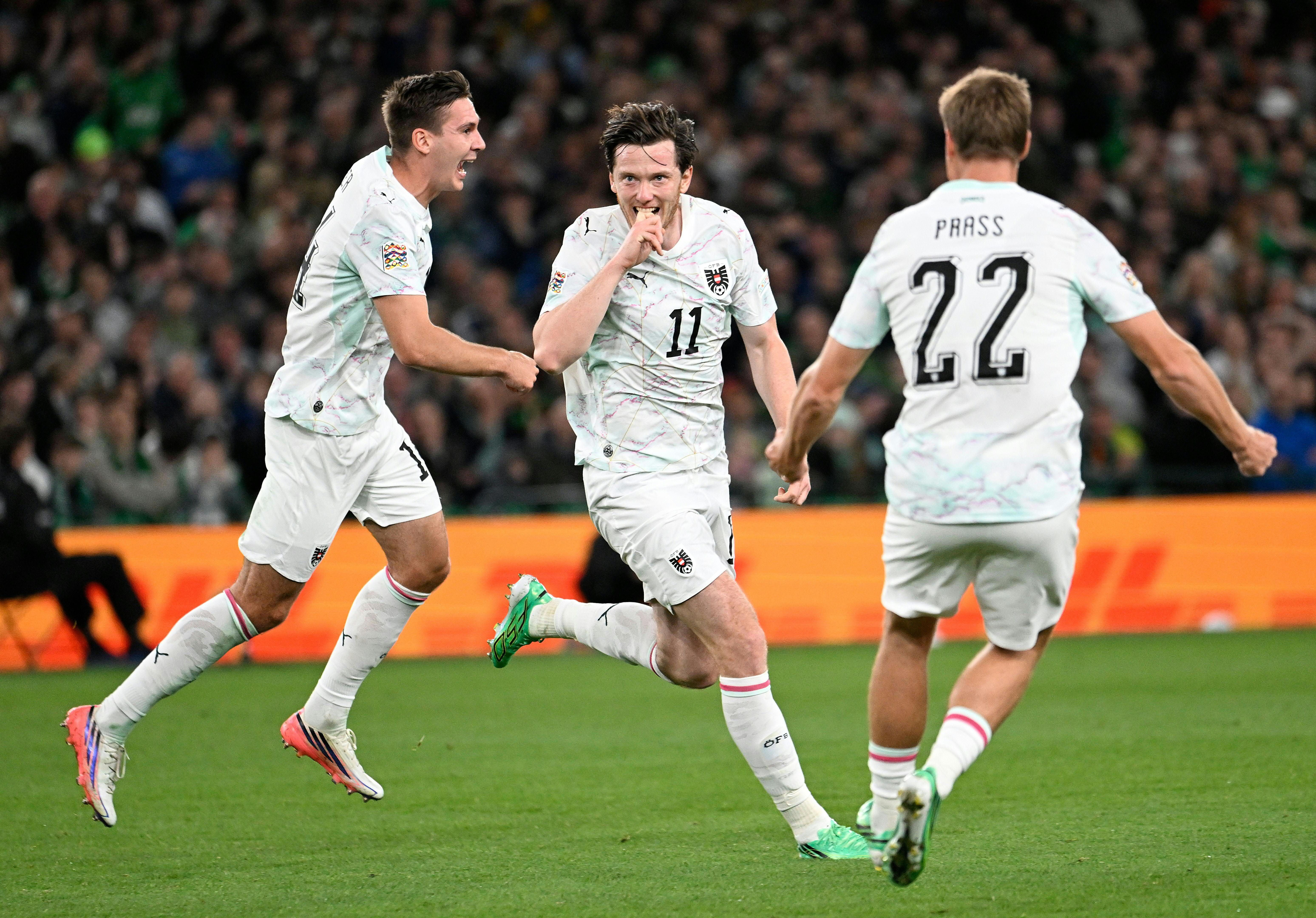 Drei österreichische Fußballspieler jubeln auf dem Spielfeld bei einem Nations-League-Spiel in Dublin.