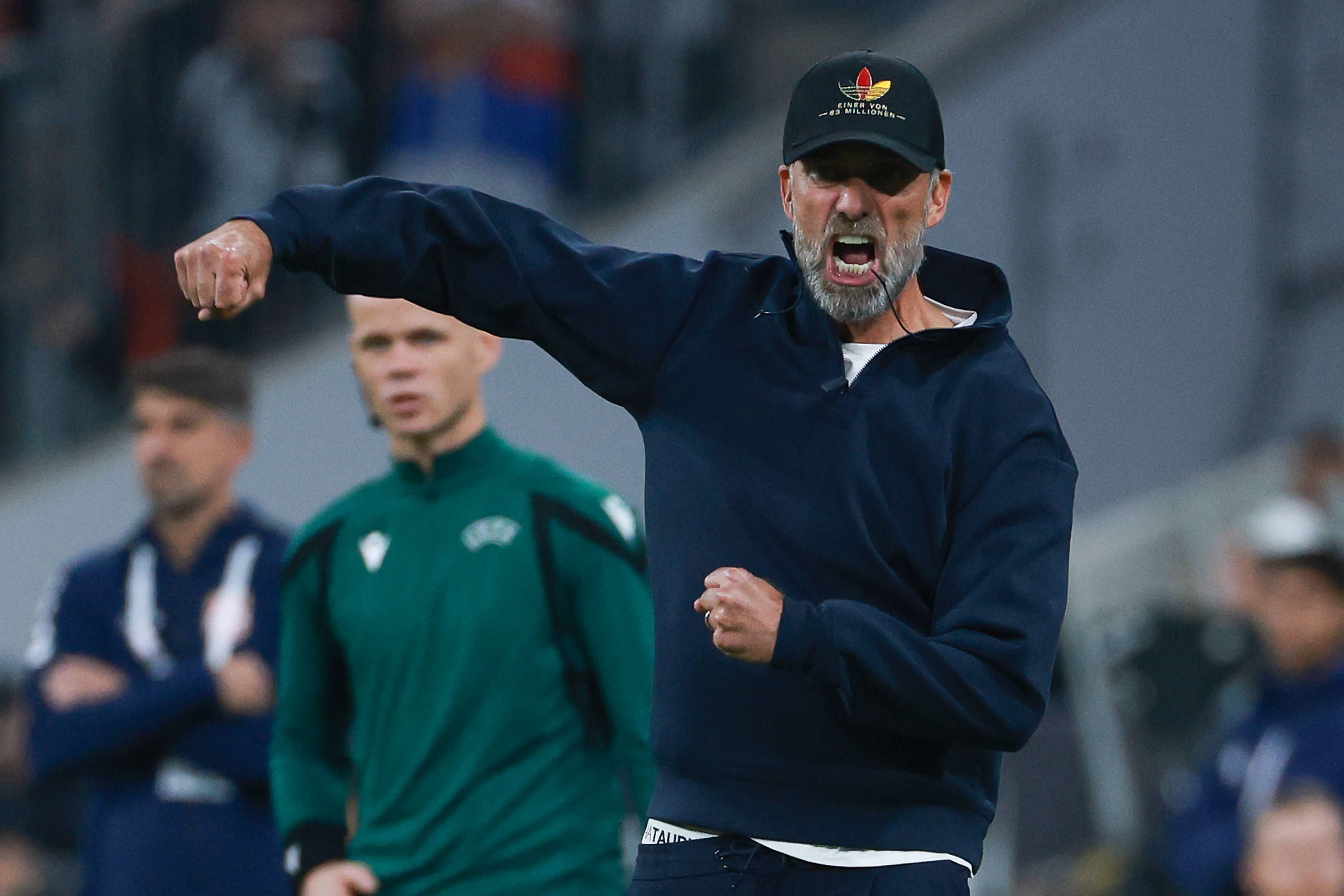 Jürgen Klopp im dunkelblauen Kapuzenpullover gestikuliert emotional an der Seitenlinie und ballt beide Fäuste.