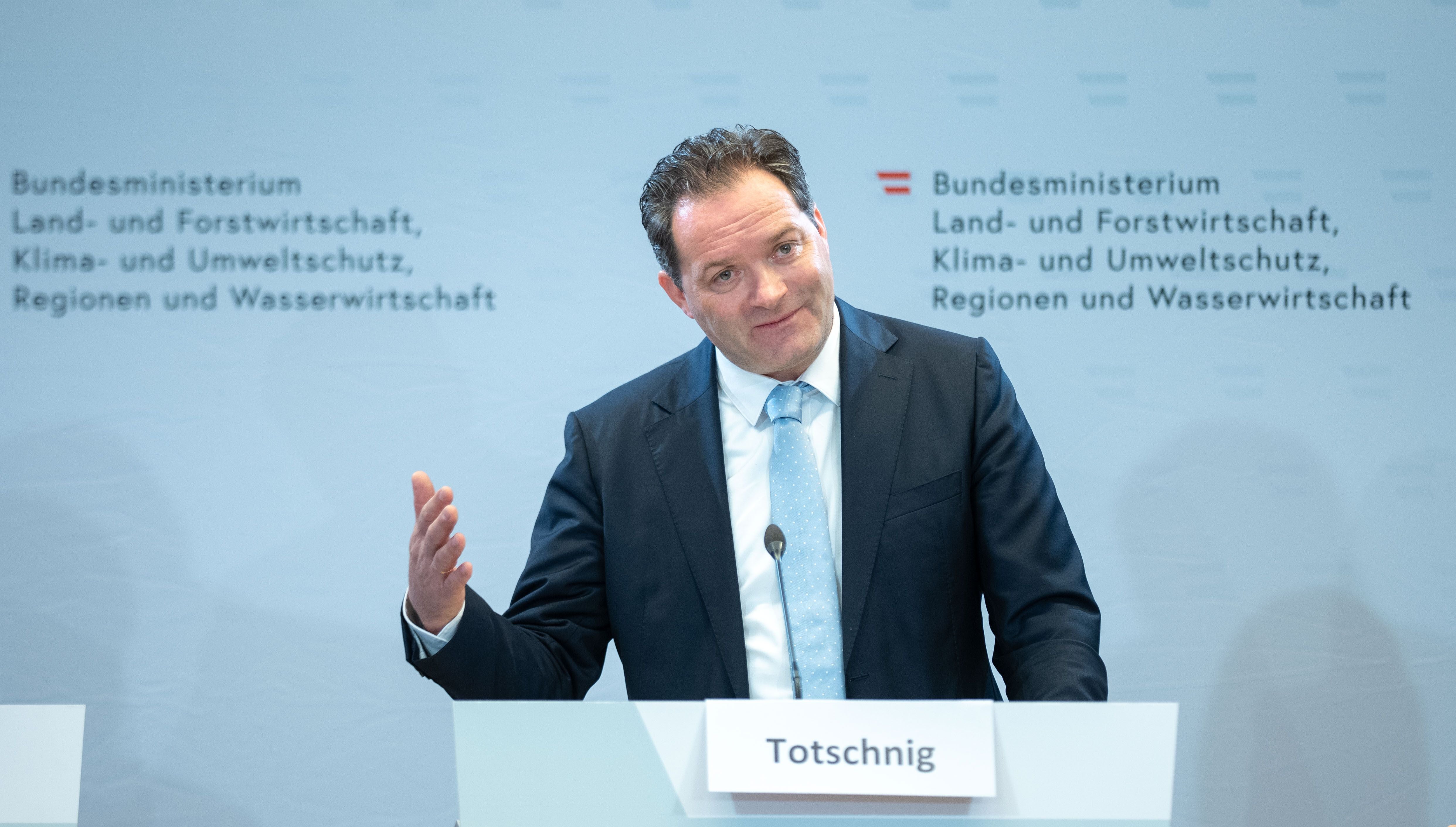 Ein Mann im Anzug spricht auf einer Pressekonferenz am Rednerpult mit Namensschild "Totschnig".
