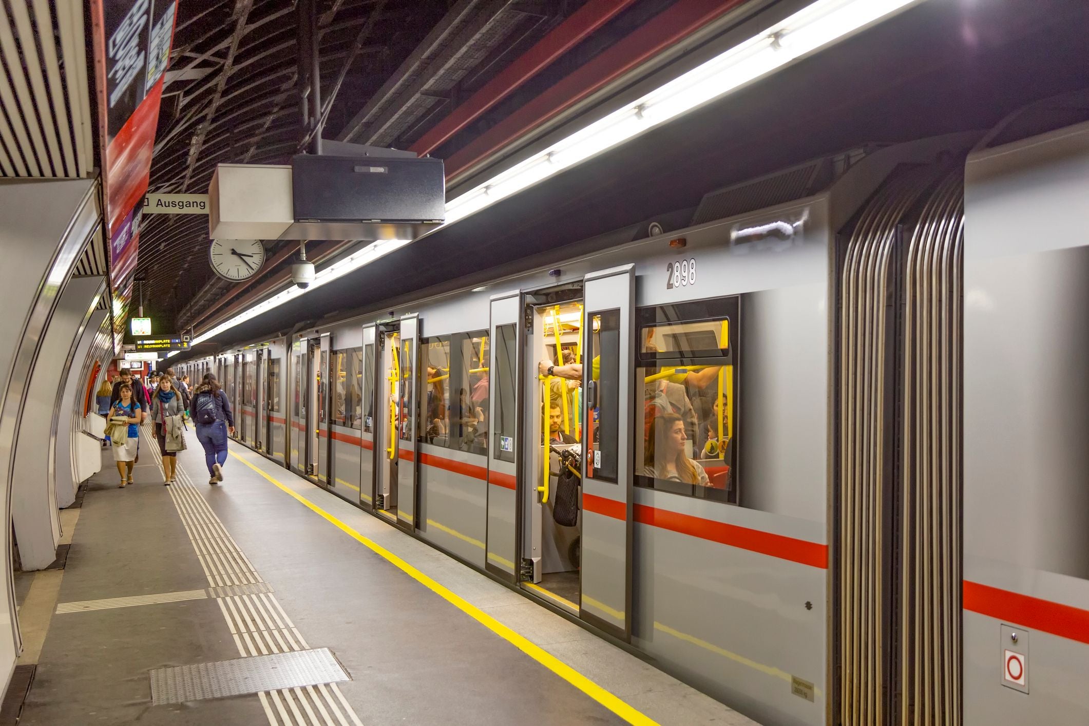 Menschen steigen in eine U-Bahn in einer belebten Station in Wien ein und aus.