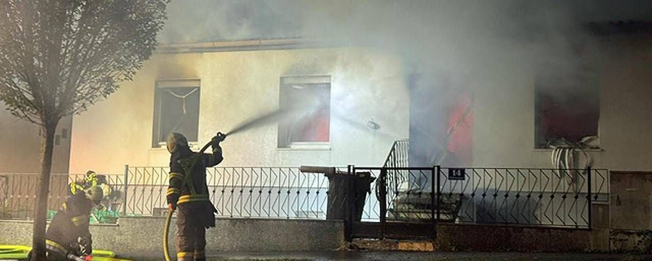 Feuerwehr löscht ein brennendes Einfamilienhaus, starke Rauchentwicklung, Nachtaufnahme.