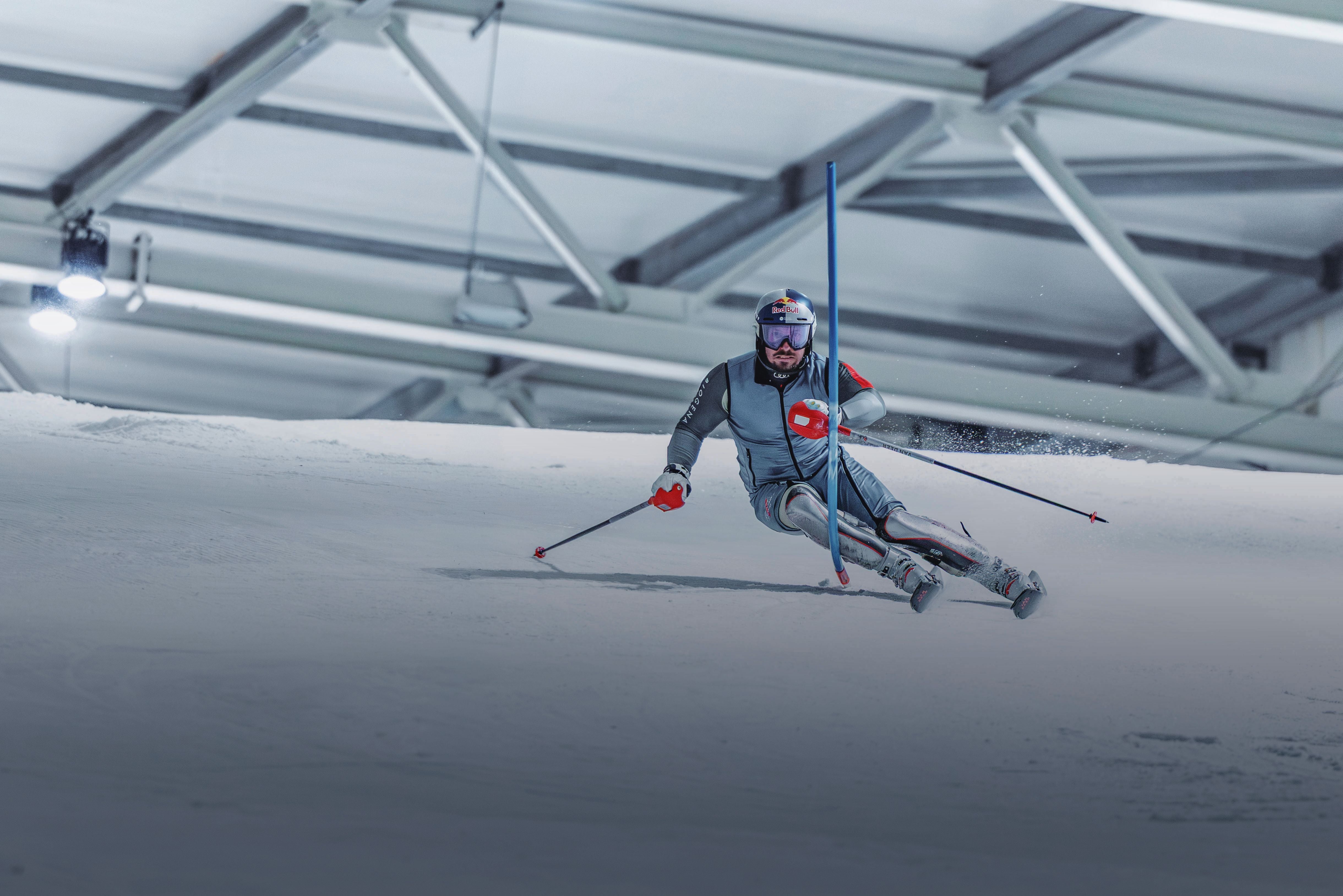 Ein Skifahrer fährt Slalom in einer Indoor-Skihalle und passiert eine blaue Stange.