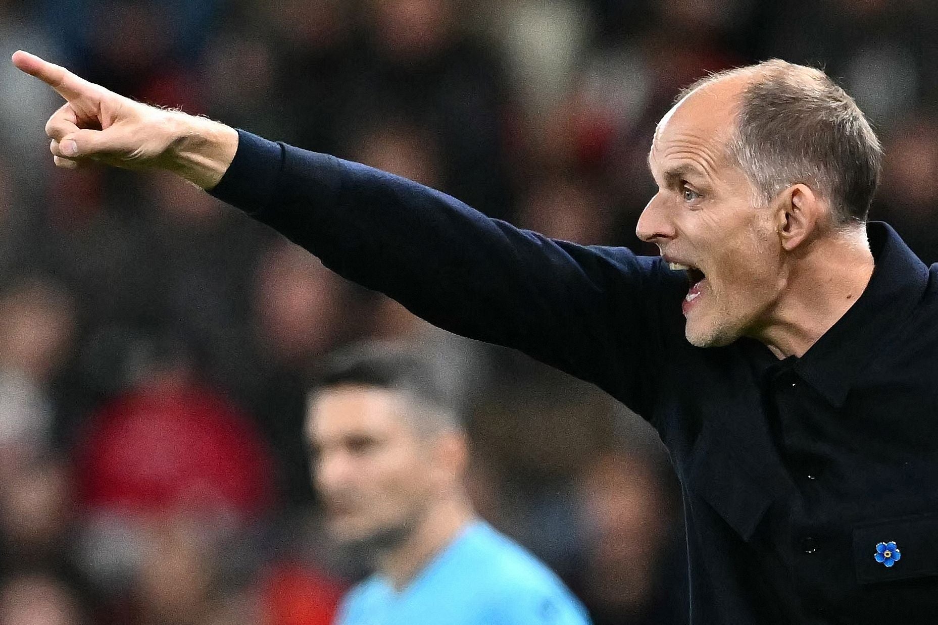 Thomas Tuchel gestikuliert und ruft Anweisungen mit erhobenem Zeigefinger am Spielfeldrand.