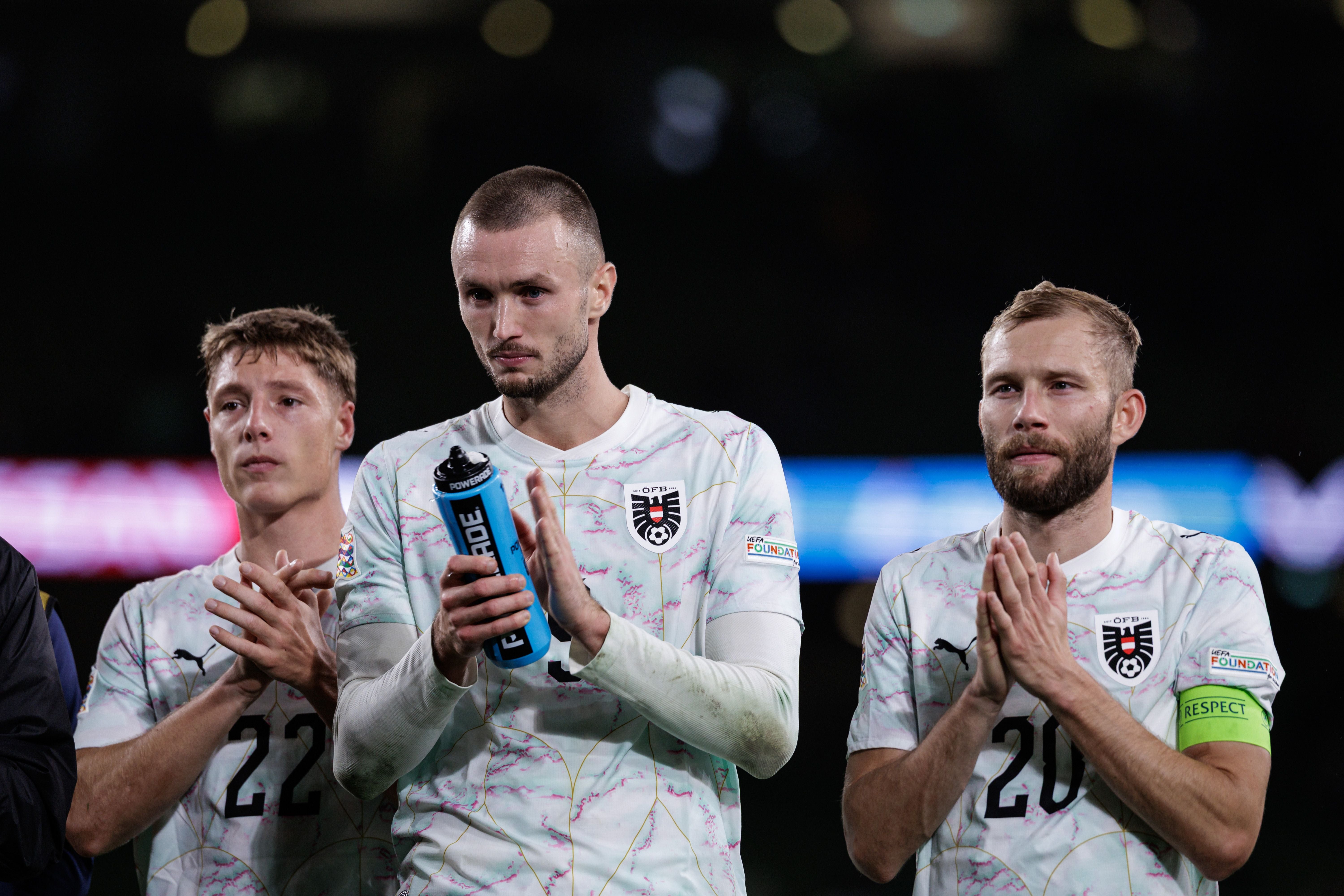 Drei österreichische Fußballspieler applaudieren nach einem Spiel im Stadion.