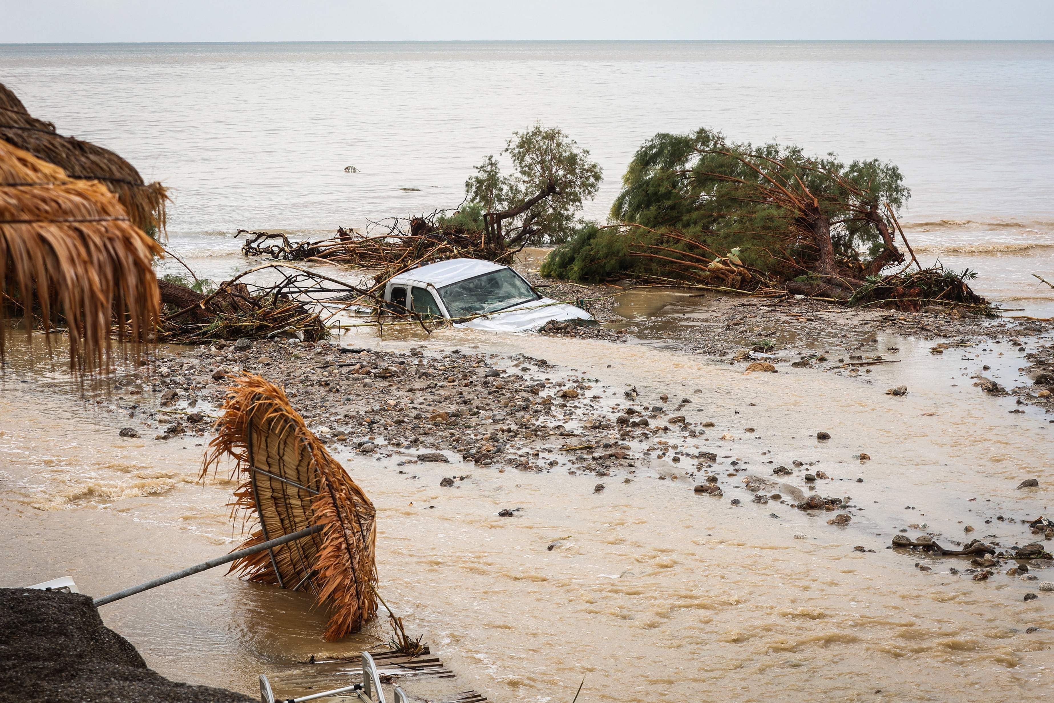 Ein überflutetes Auto und entwurzelte Bäume liegen am Strand nach starkem Regen auf Kreta.