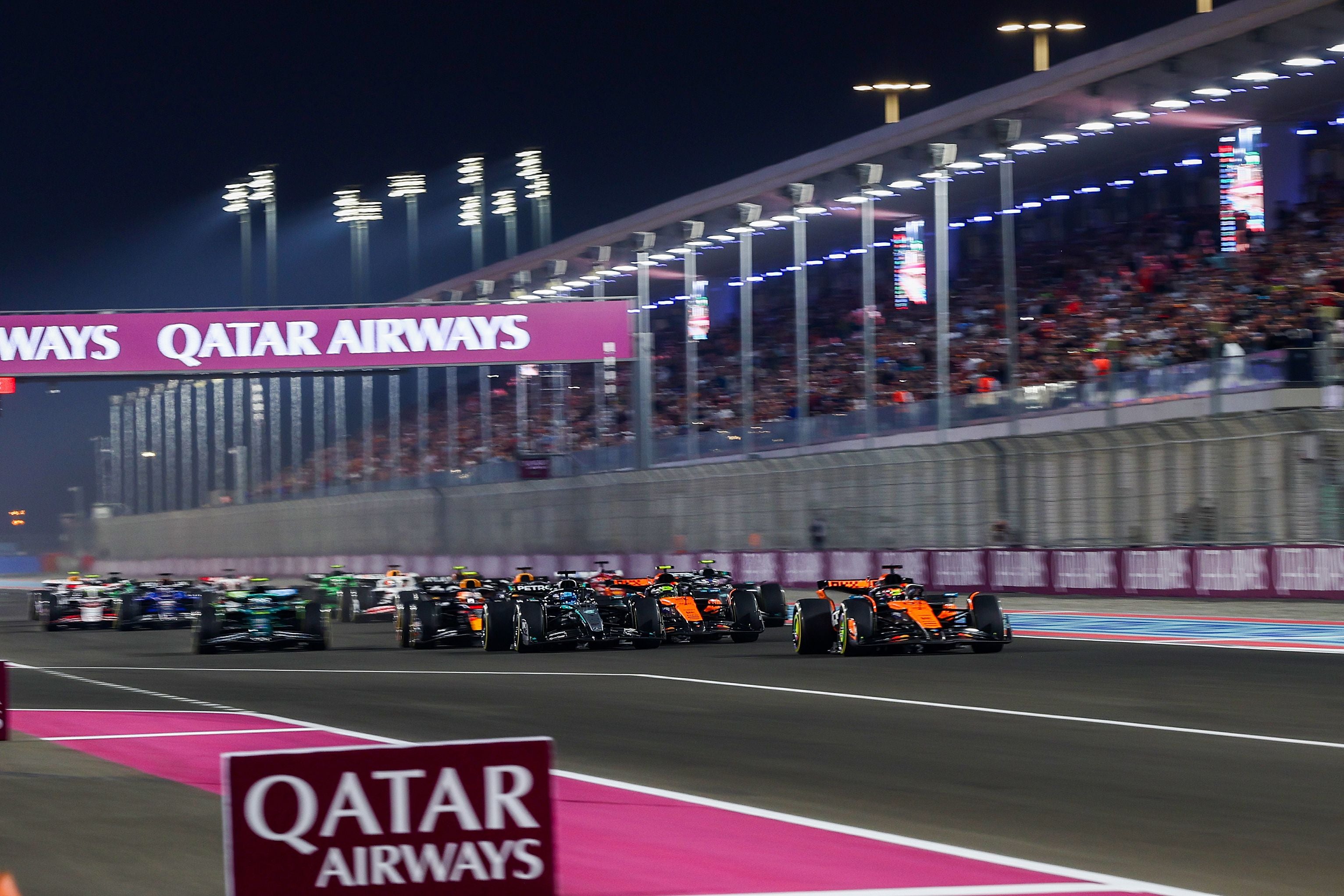 Formel-1-Autos starten beim Nachtrennen in Katar vor vollen Tribünen am Lusail International Circuit.