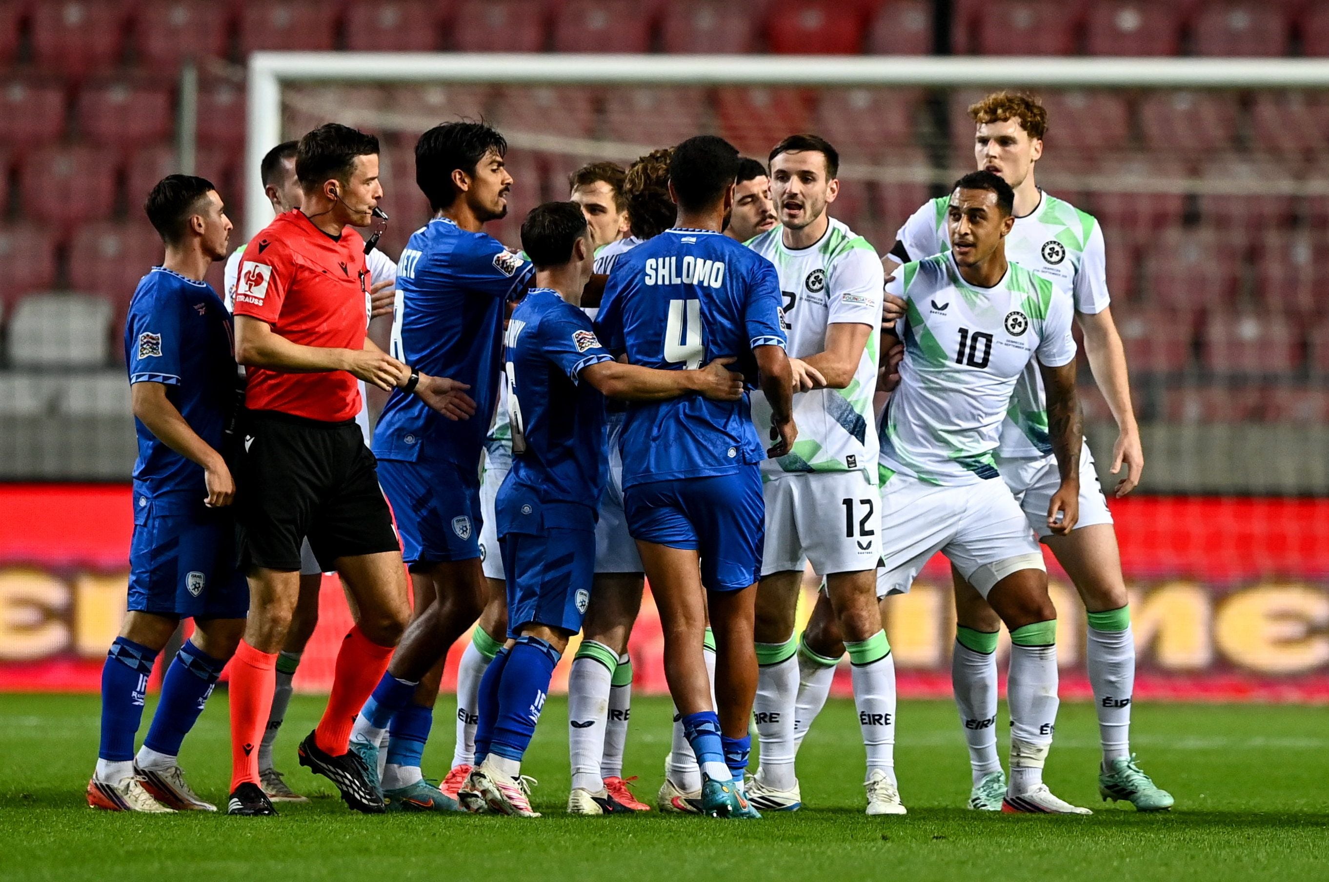 Spieler aus Israel und Irland geraten während eines Fußballspiels in einen Streit, der Schiedsrichter greift ein.