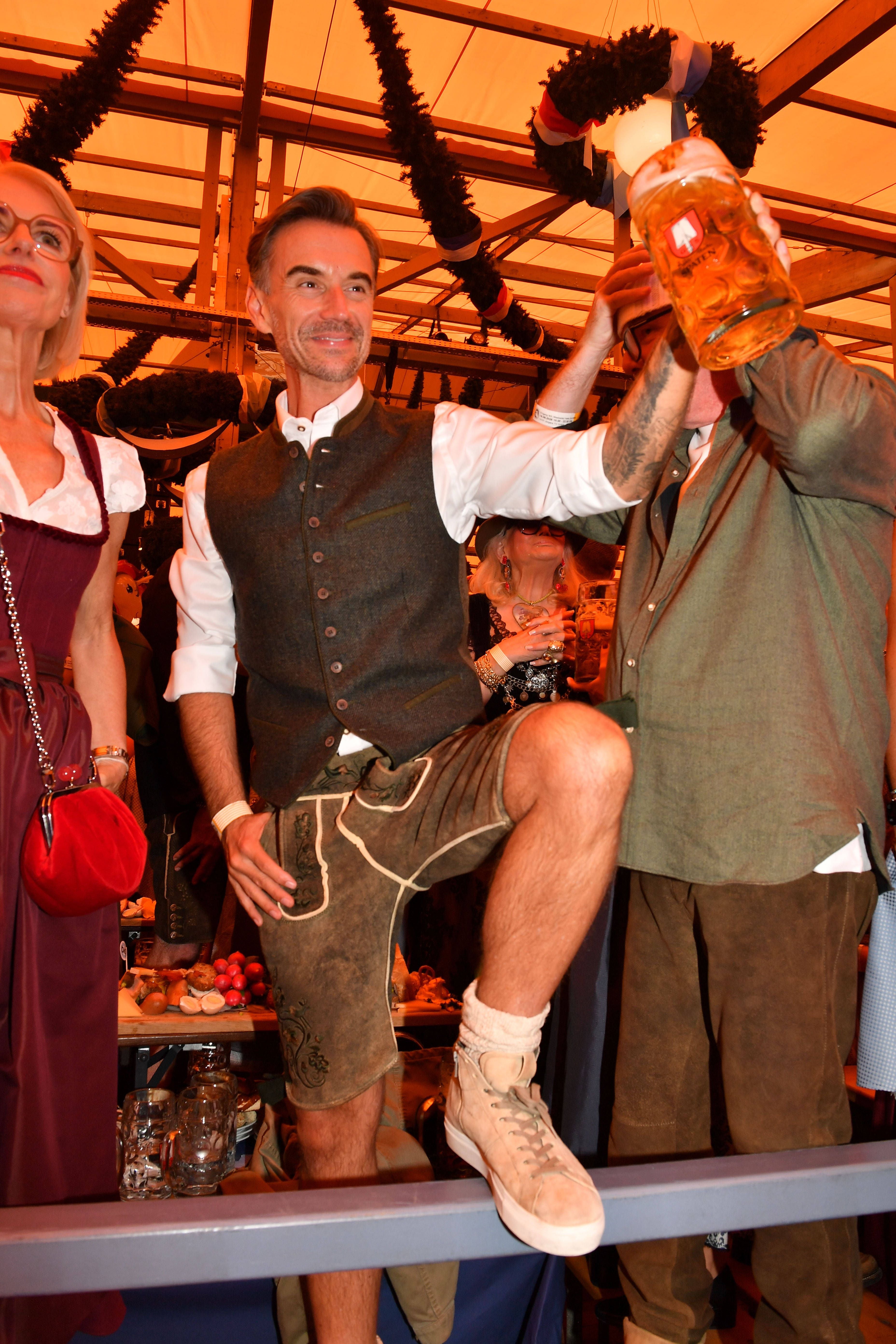 Mann in Tracht mit Maßkrug feiert im Festzelt auf dem Oktoberfest in München.