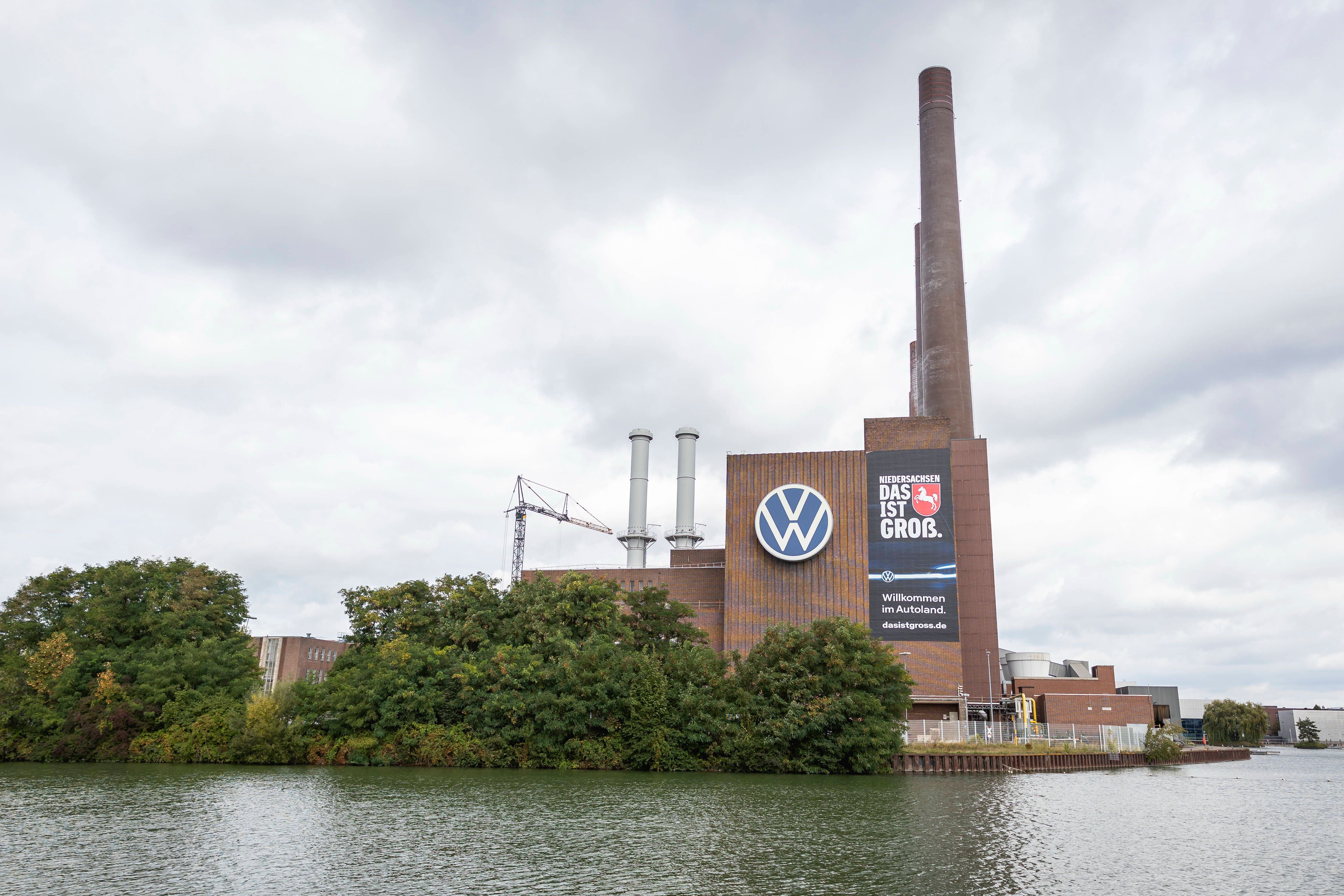 Das Volkswagen-Werk in Wolfsburg mit großem VW-Logo und Schornsteinen am Wasser.