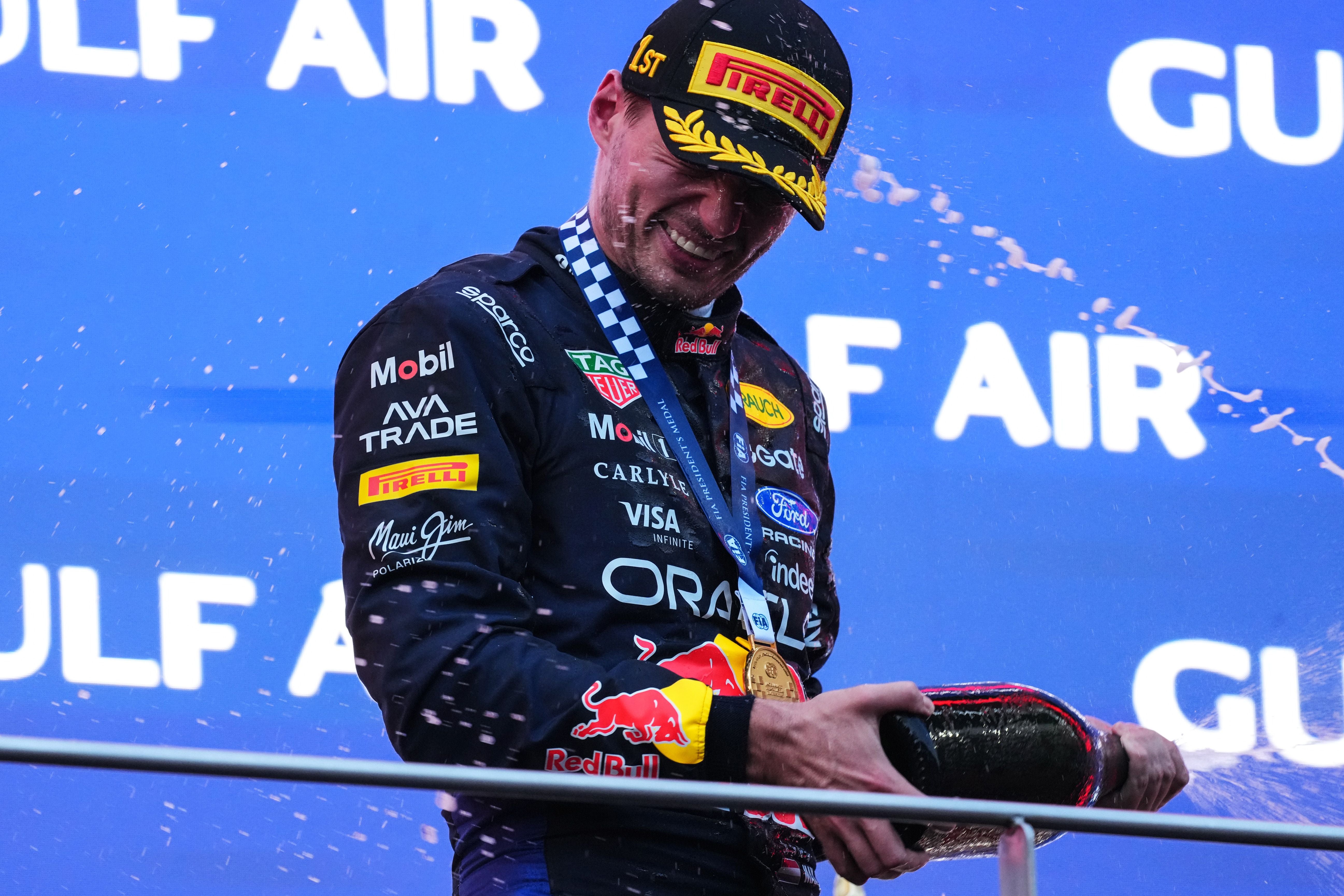 Ein Formel-1-Fahrer feiert auf dem Podium und spritzt mit Champagner.