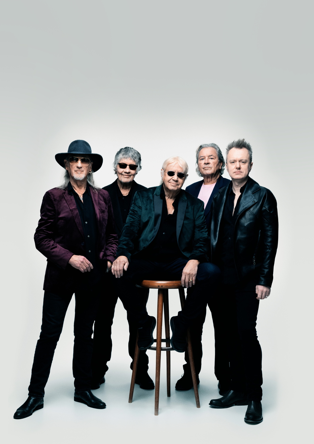 Fünf Männer posieren als Rockband Deep Purple vor hellem Hintergrund.