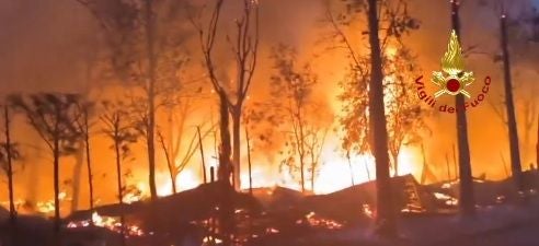 Großes Waldbrand am Gardasee mit lodernden Flammen und rauchenden Bäumen.
