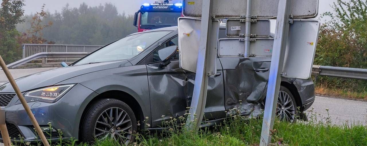 Ein graues Auto ist seitlich stark beschädigt, nachdem es gegen ein Verkehrsschild geprallt ist.