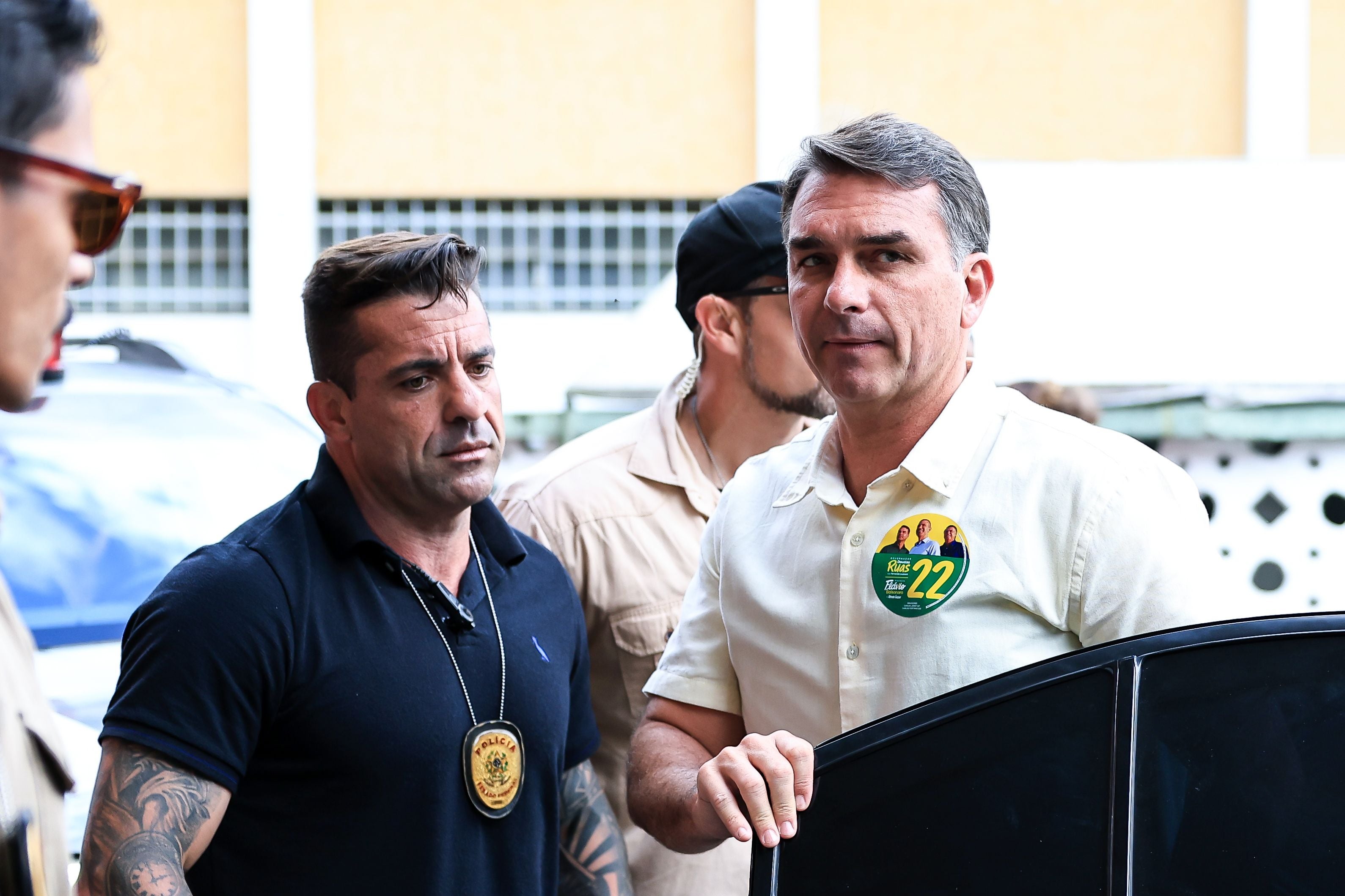 Flávio Bolsonaro steigt am Wahltag mit Begleitern aus einem Auto in Rio de Janeiro aus.