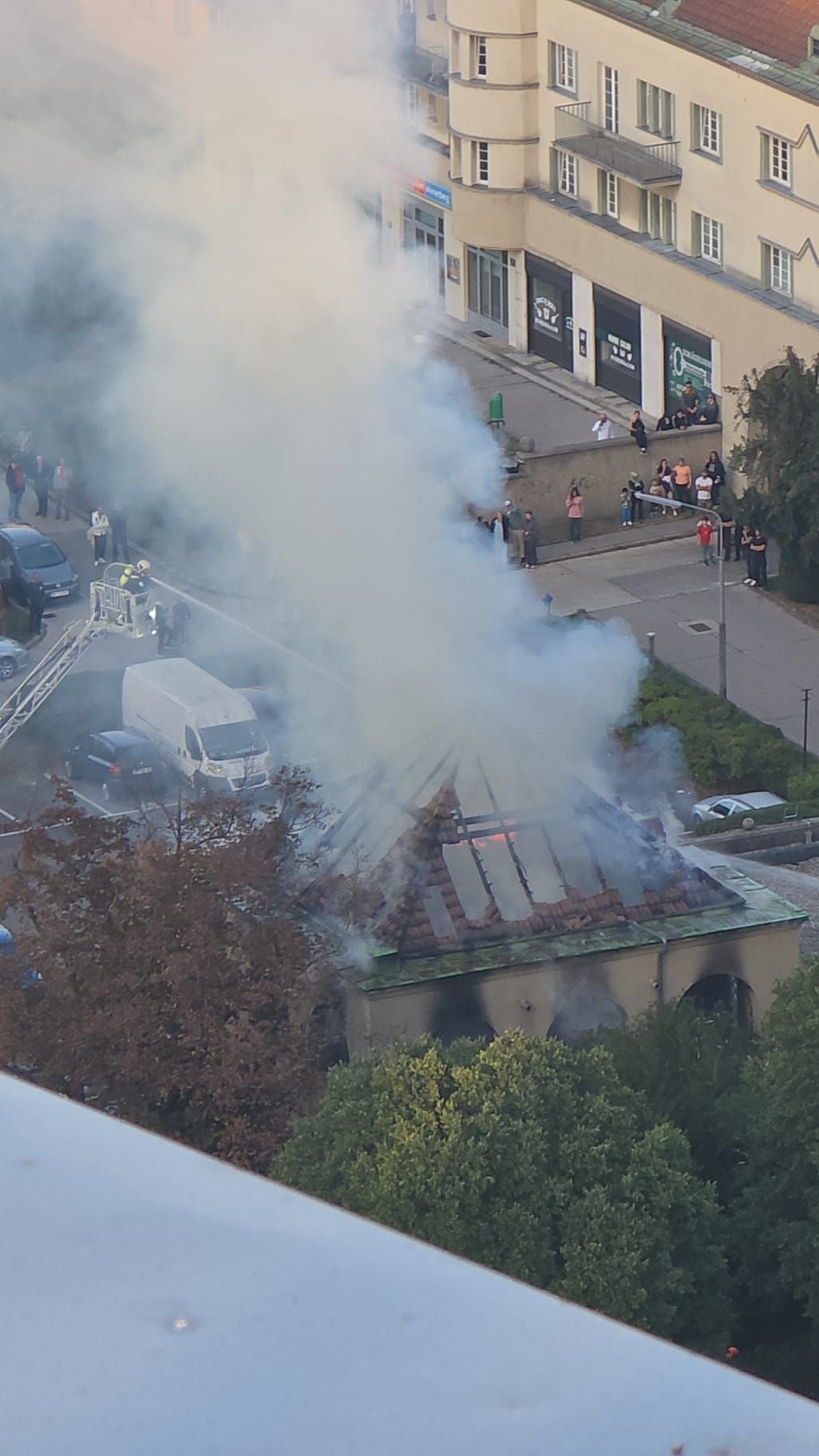 Dichter Rauch steigt aus dem brennenden Dach eines Gebäudes im Gemeindebau Fliederhof auf.