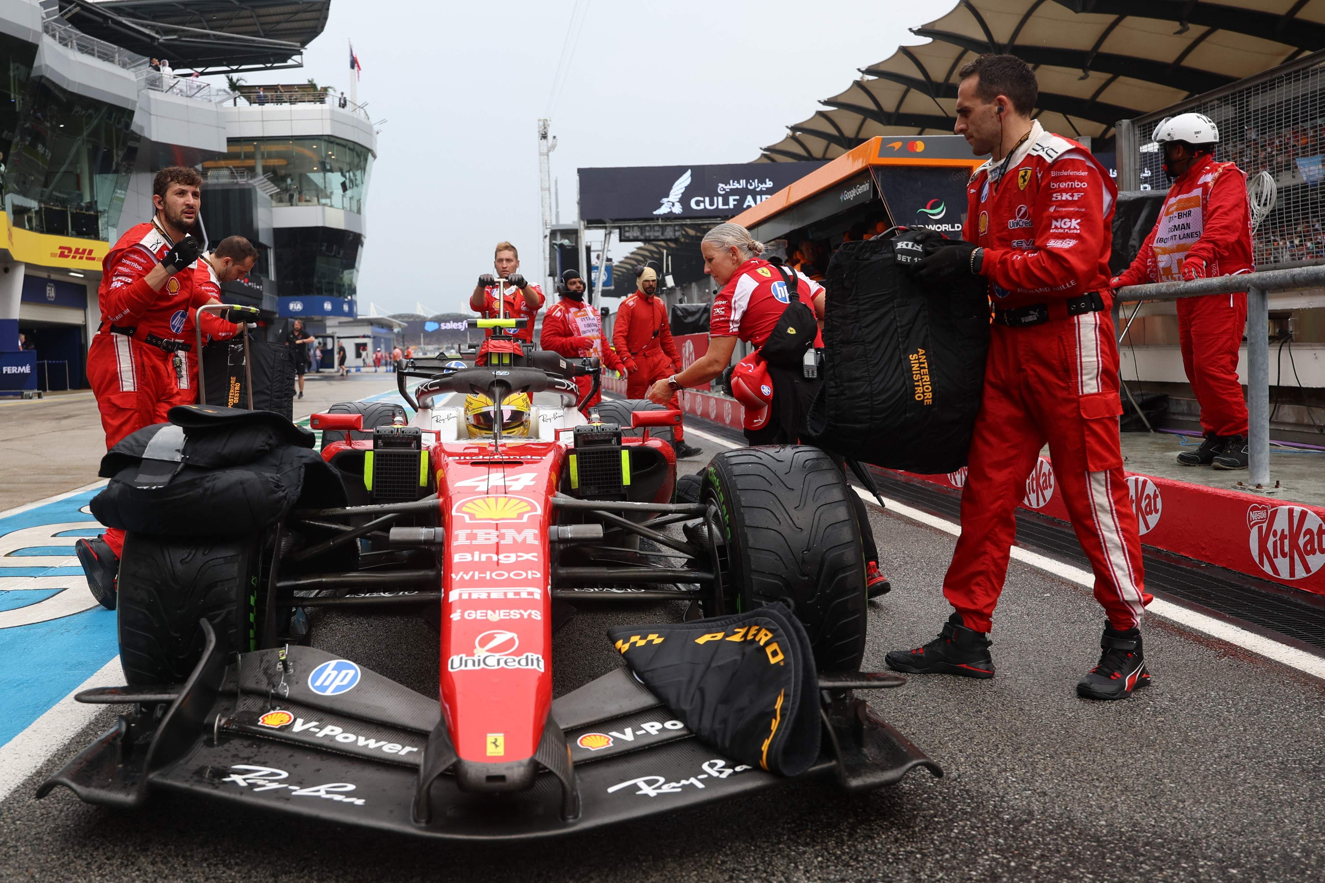 Ferrari-Mechaniker entfernen Reifenwärmer von einem Formel-1-Auto in der Boxengasse.