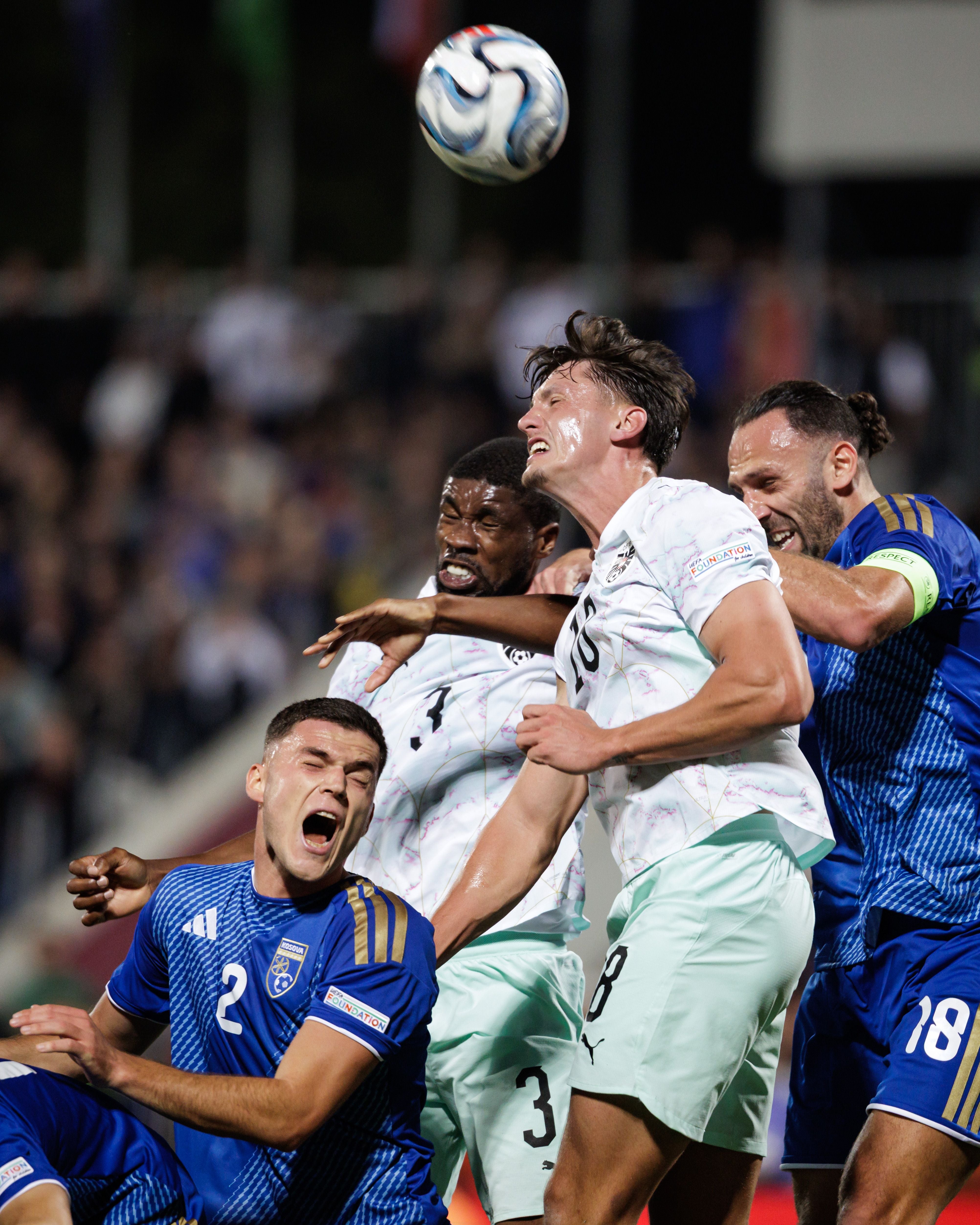 Fußballspieler kämpfen im Strafraum um den Ball während eines intensiven Kopfballduells.