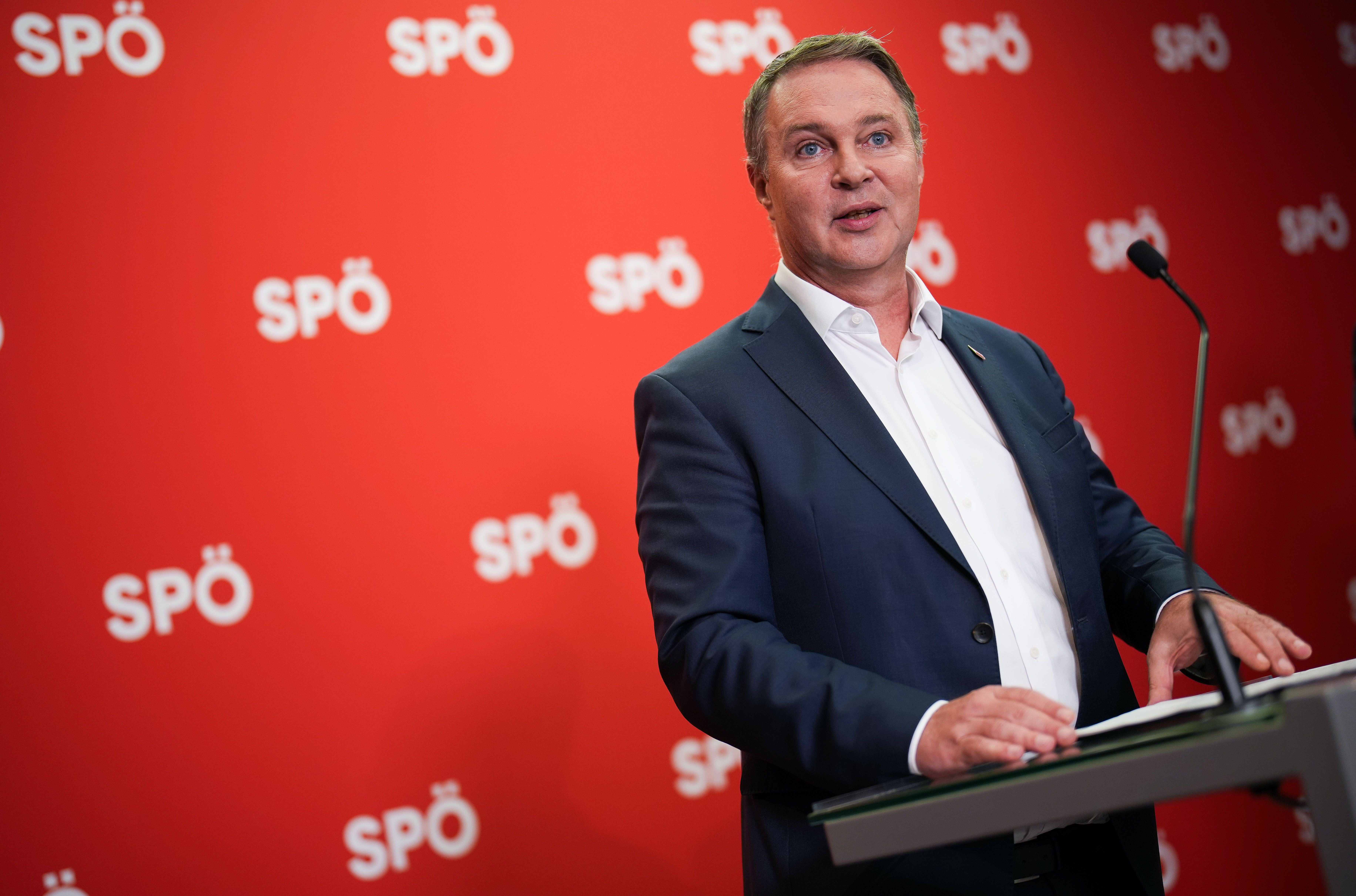 Ein Mann hält eine Rede an einem Rednerpult vor rotem Hintergrund mit SPÖ-Logos.