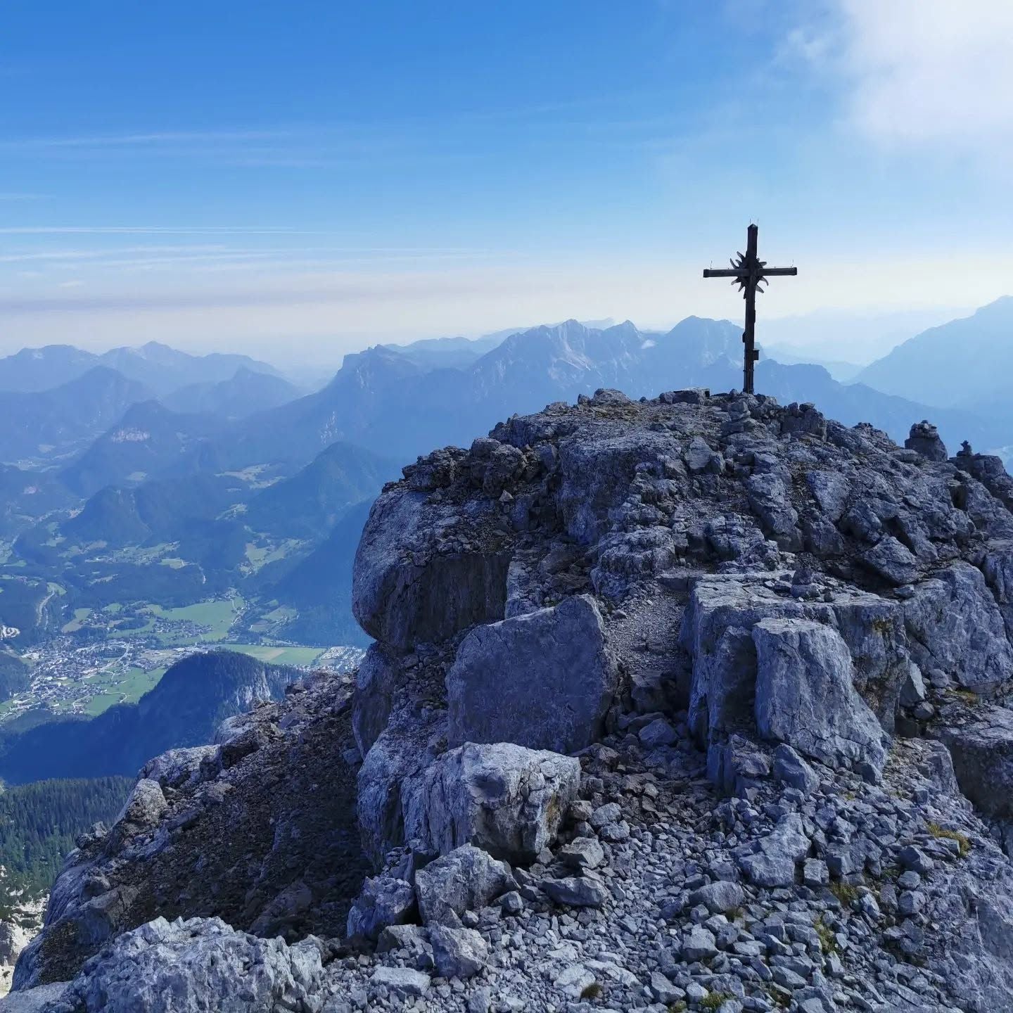 Gipfelkreuz auf felsigem Berggipfel des Ochsenhorns mit Blick auf das Tal und umliegende Berge.