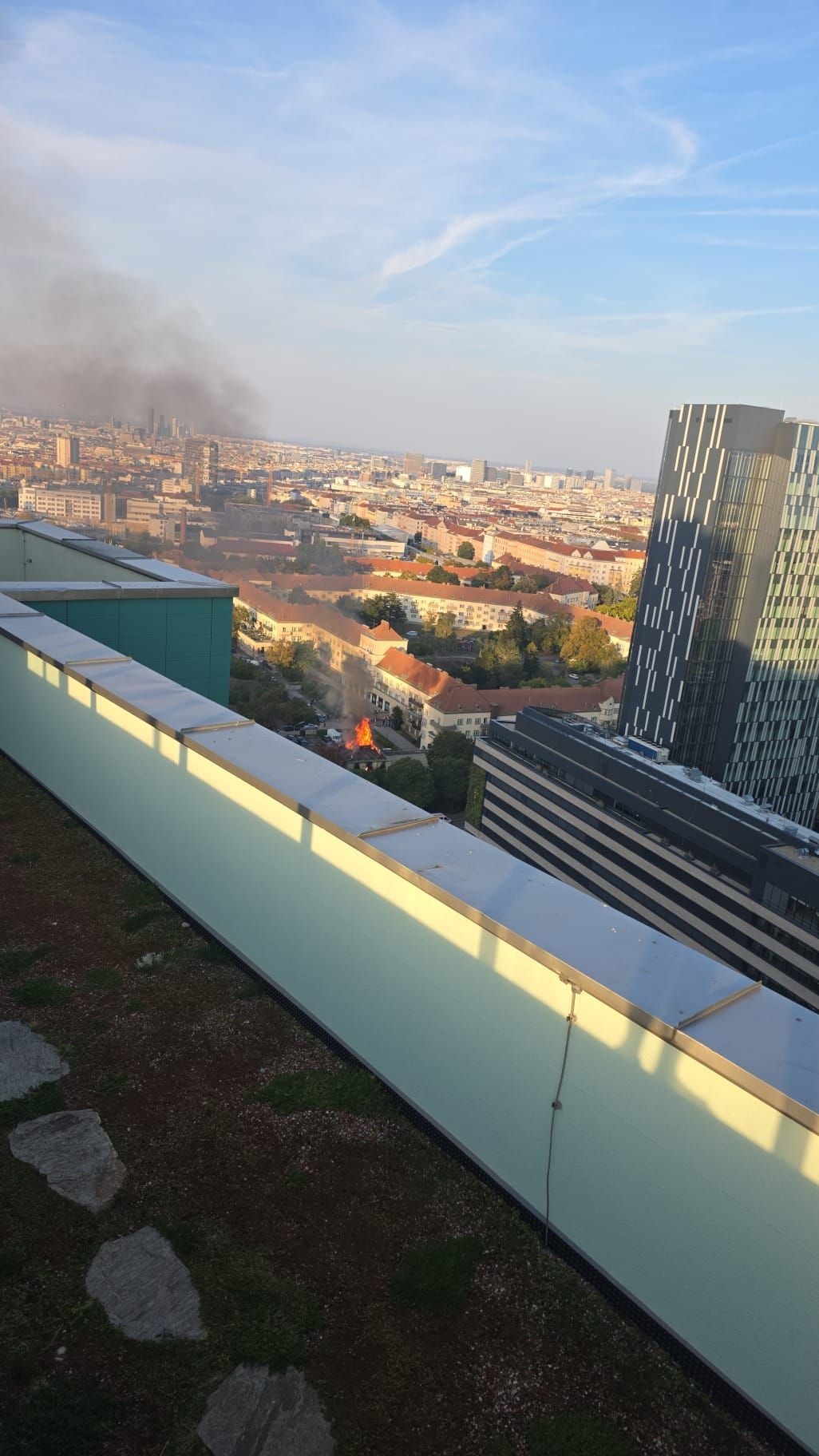 Blick auf Stadt mit brennendem Haus und aufsteigendem Rauch im Fliederhof-Gemeindebau.