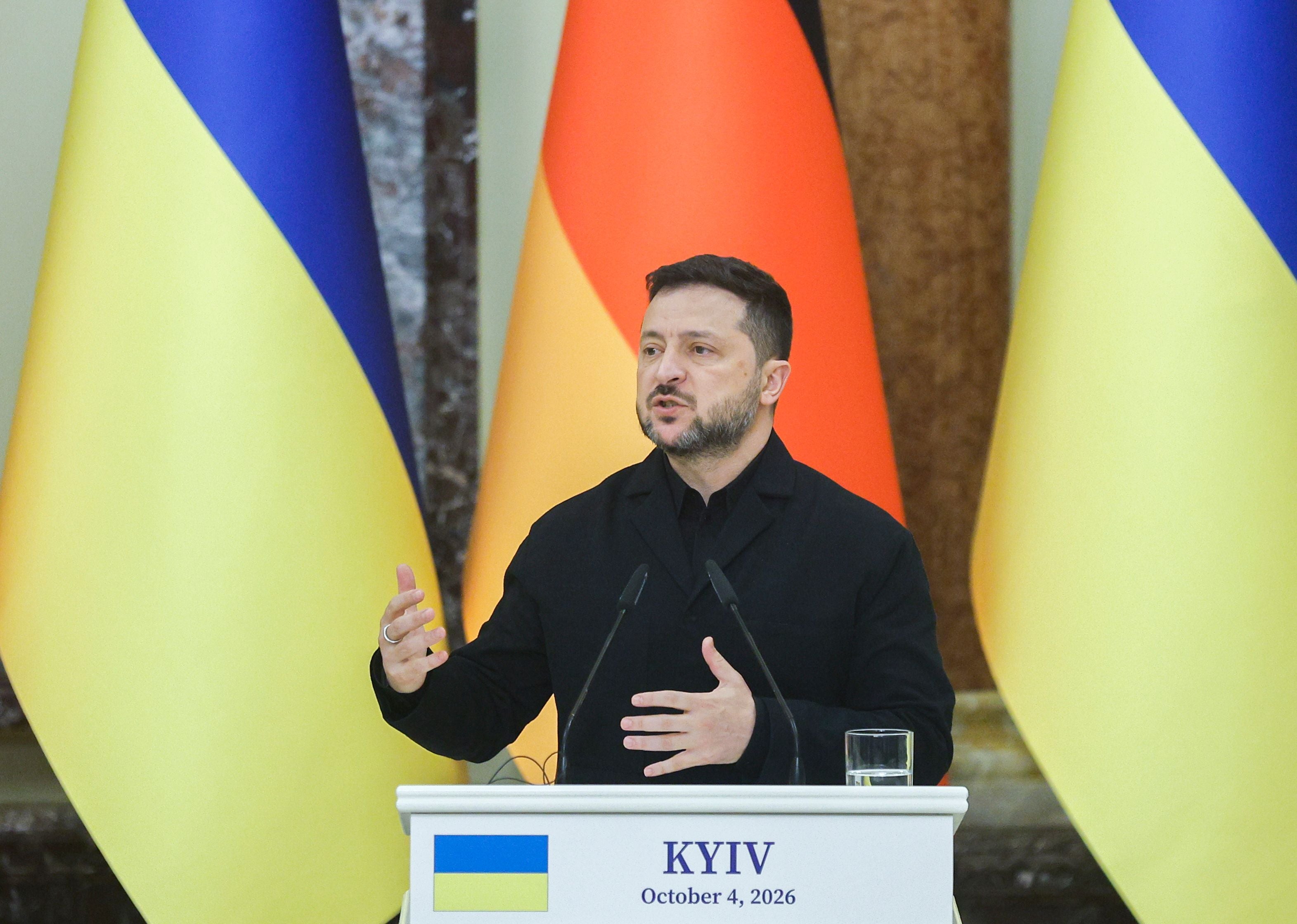 Der ukrainische Präsident spricht bei einer Pressekonferenz vor ukrainischen und deutschen Flaggen.