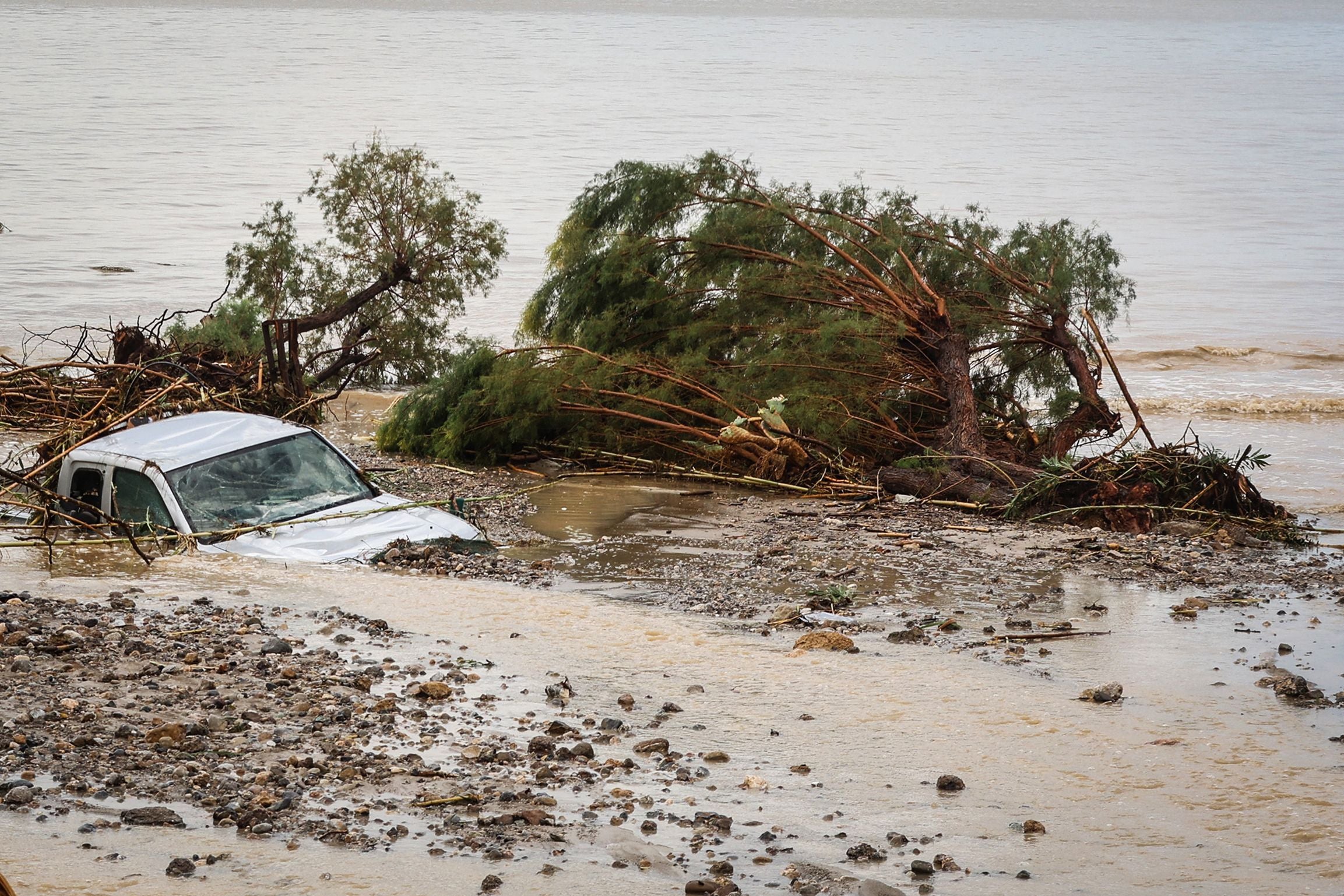 Ein Auto und entwurzelte Bäume liegen nach einer Überschwemmung teilweise im Meer bei Kreta.
