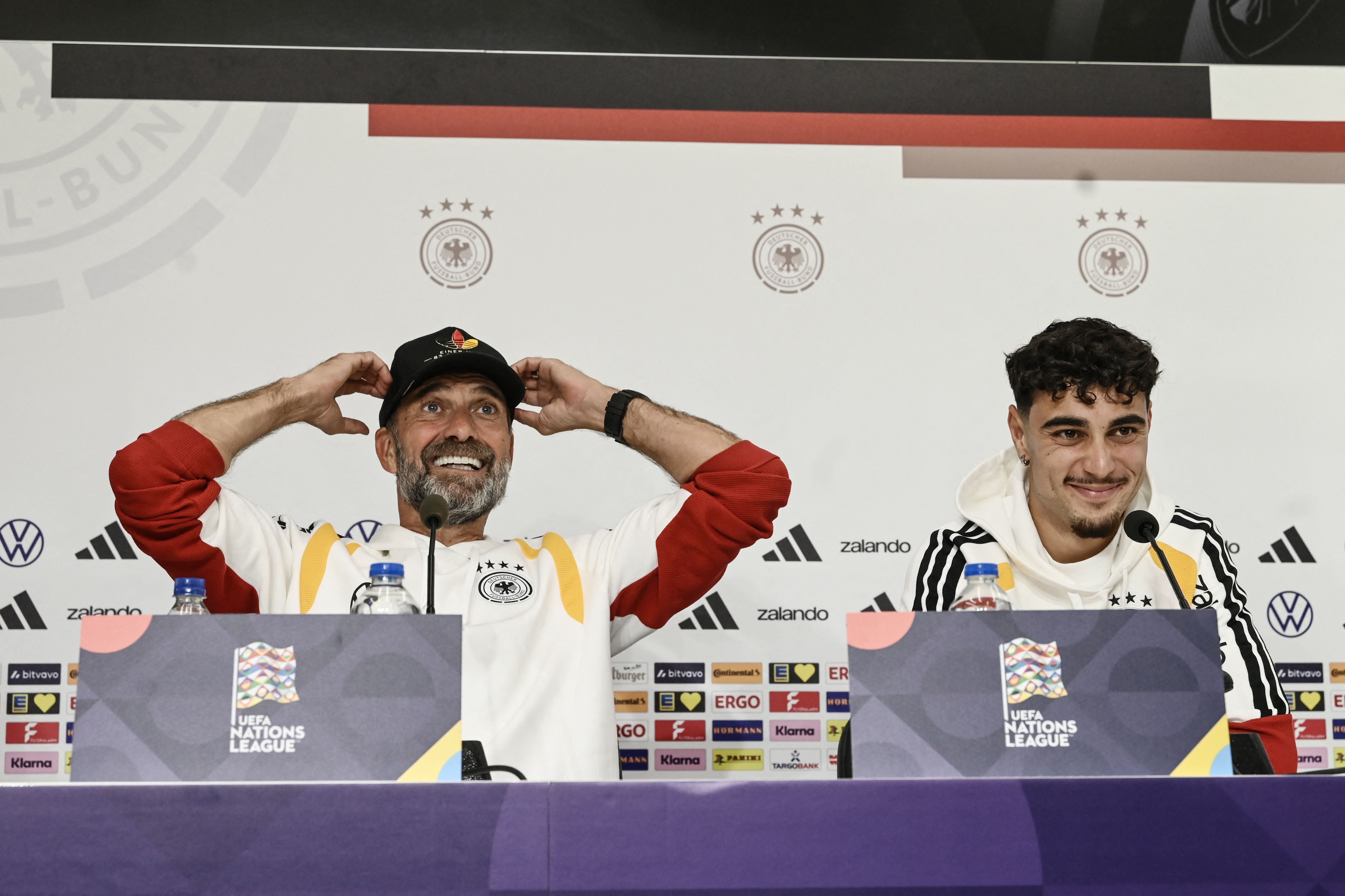 Zwei Männer bei einer Pressekonferenz der UEFA Nations League, einer lacht, der andere lächelt.