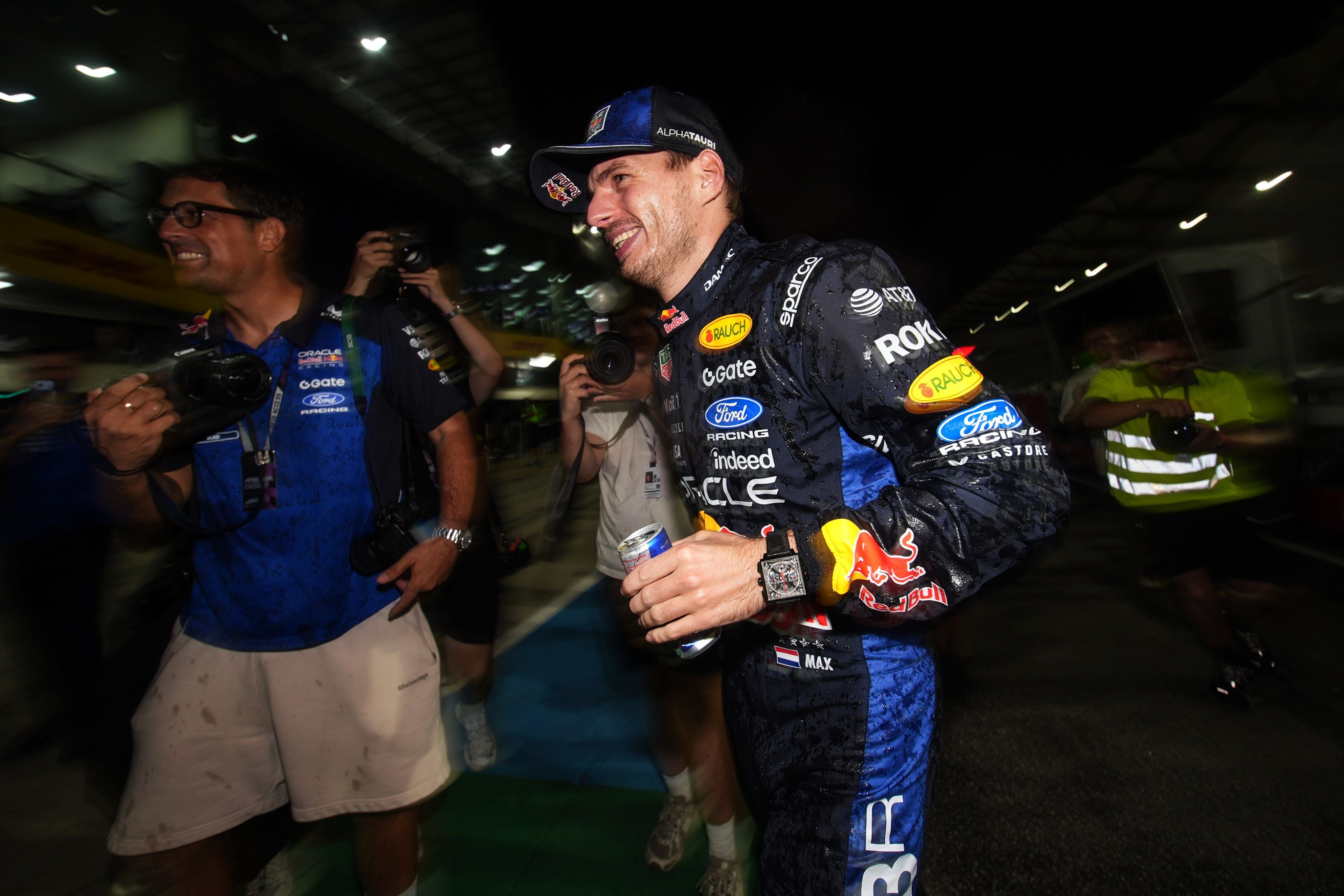 Max Verstappen feiert im Rennanzug mit seinem Team nach einem Formel-1-Sieg bei Nacht.