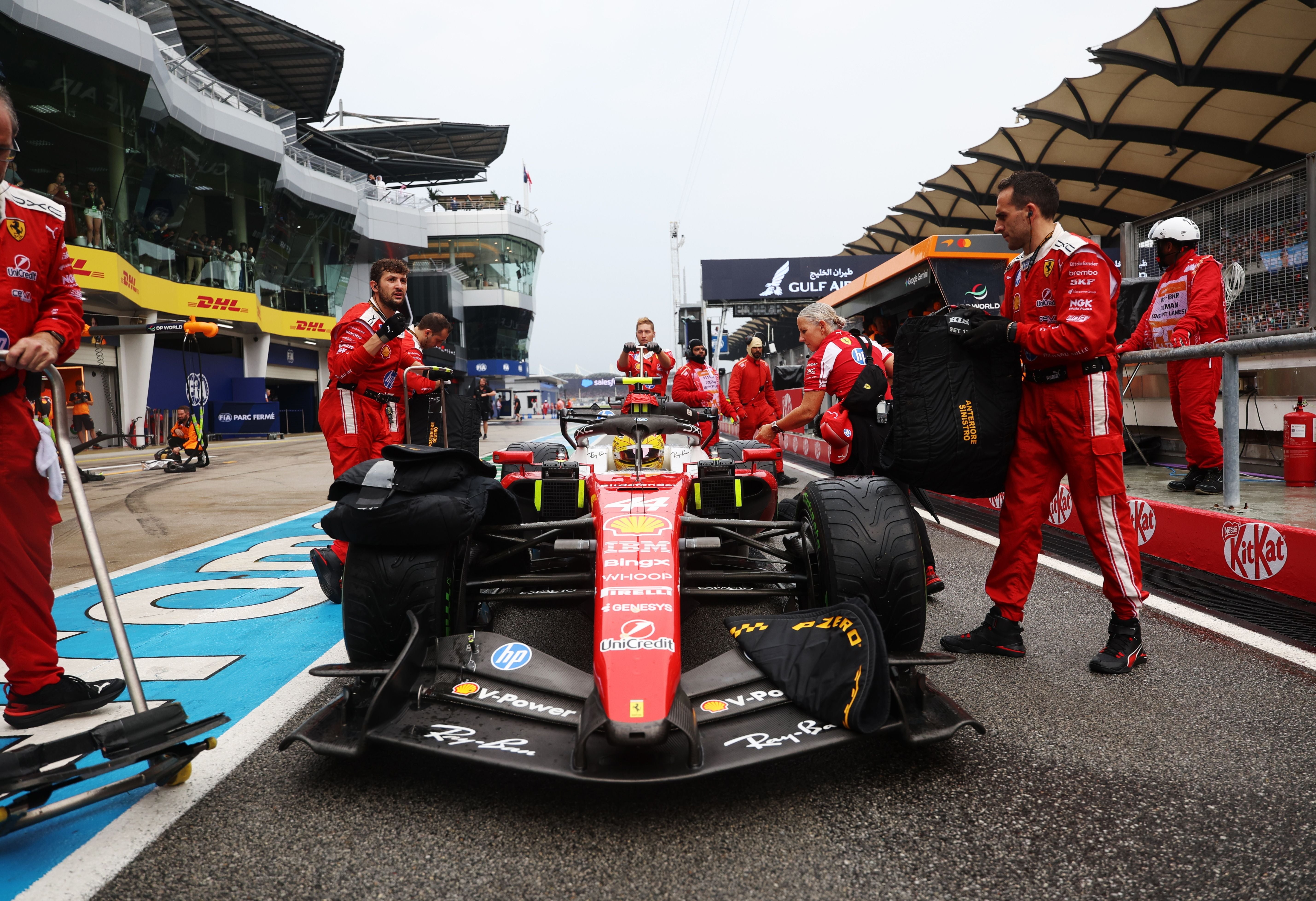 Ferrari-Team bereitet ein Formel-1-Auto in der Boxengasse auf nasser Strecke vor.