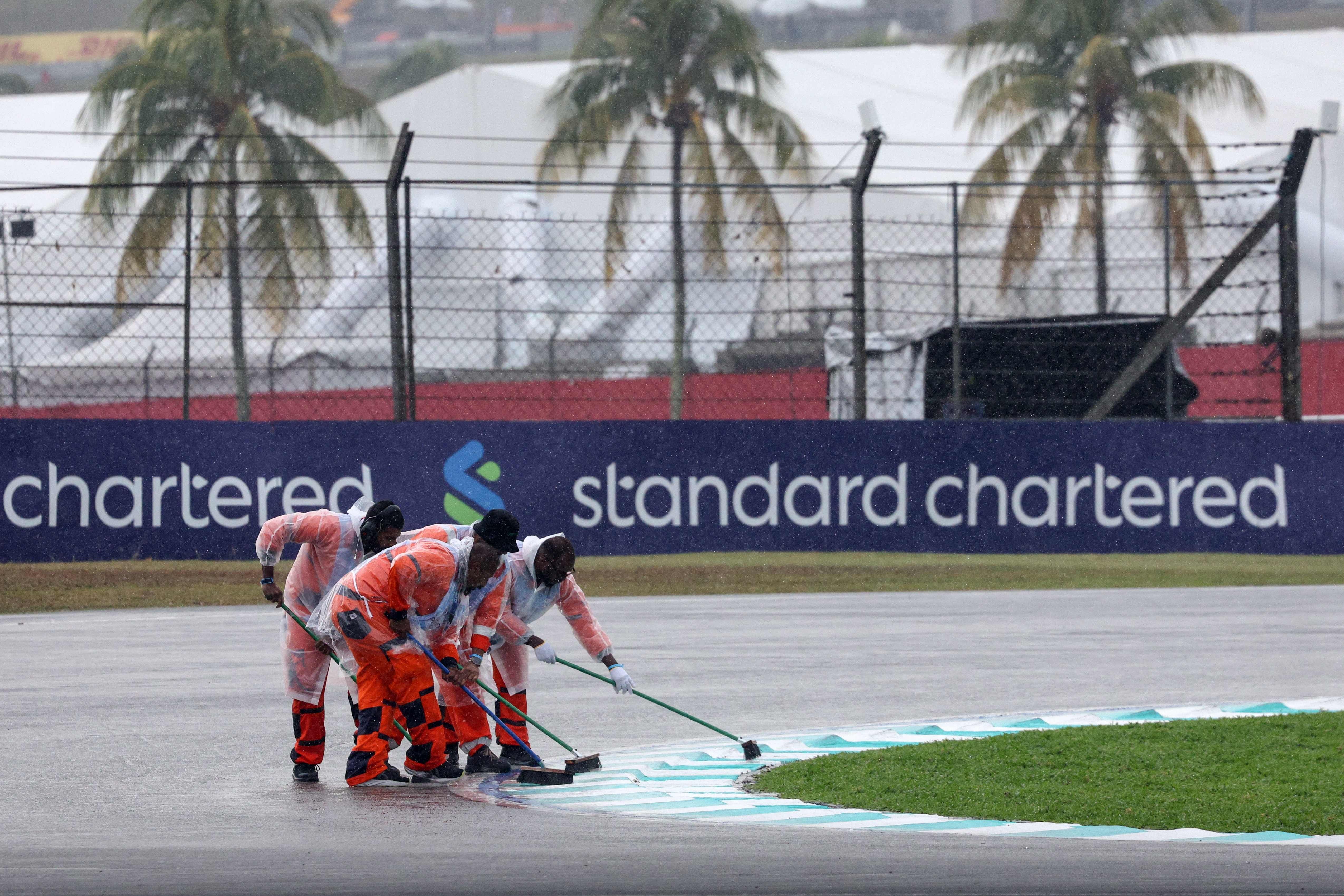 Streckenposten fegen bei Regen Wasser von der Formel-1-Rennstrecke in Sepang.