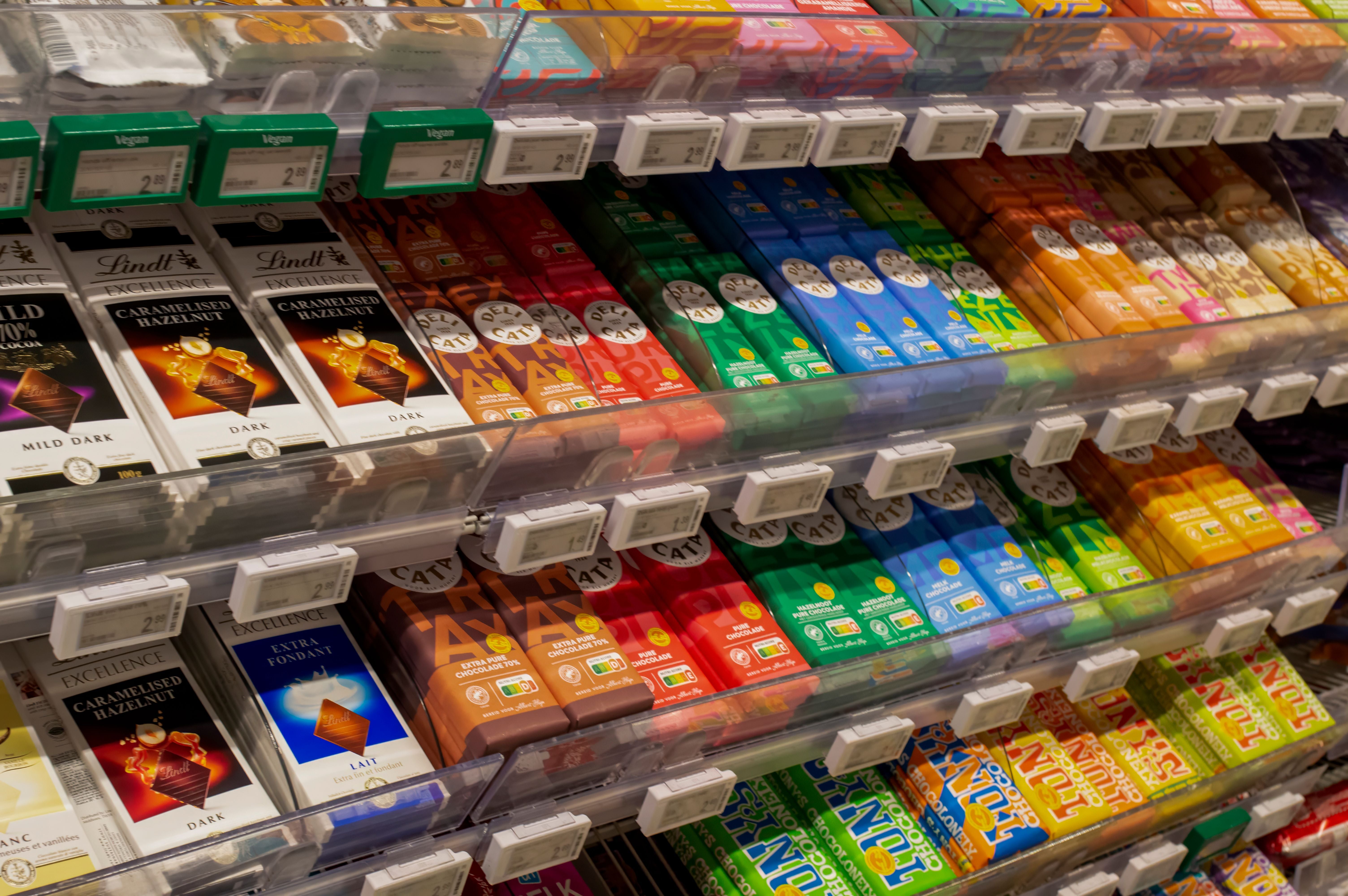 Verschiedene Schokoladentafeln in bunten Verpackungen im Supermarktregal.