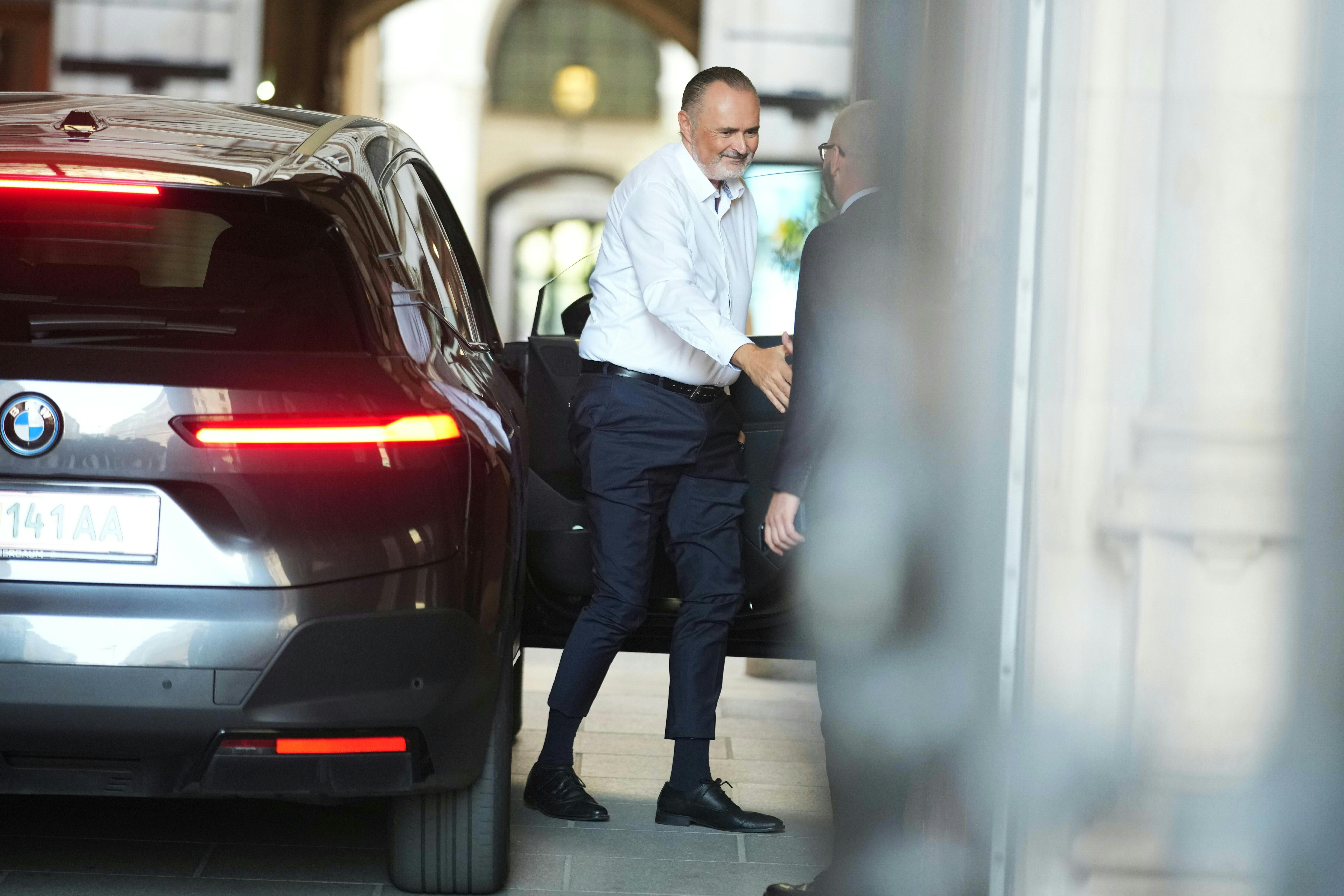 Ein Mann steigt aus einem Auto und begrüßt einen anderen Mann mit einem Händedruck.