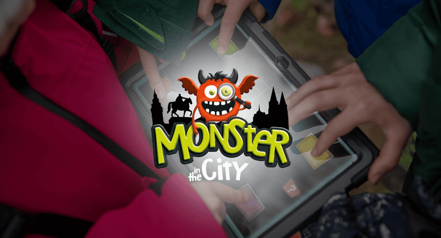 Mehrere Hände bedienen ein Tablet mit dem Logo „Monster in the City“ und Comic-Monster-Grafik.