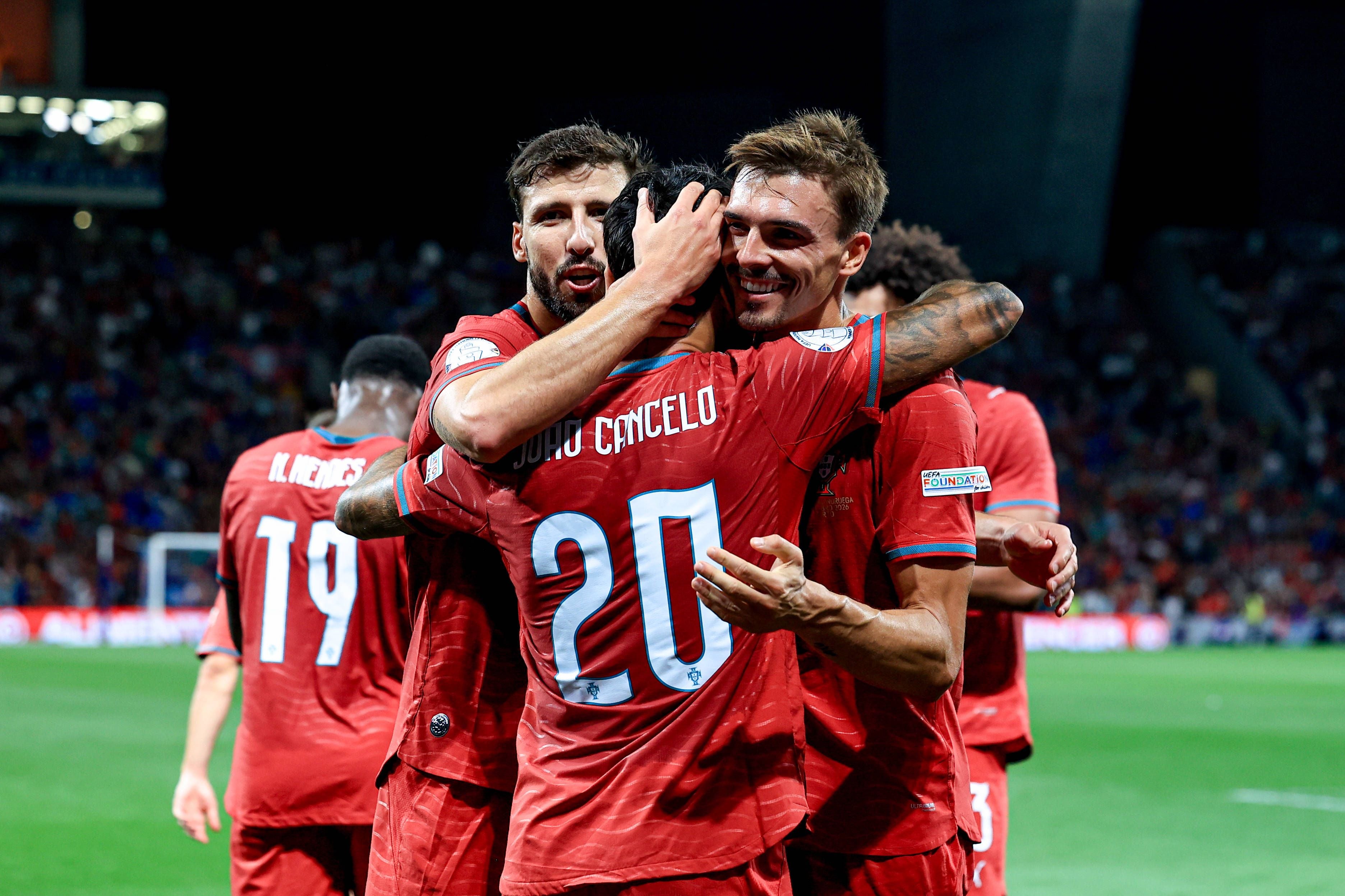 Portugiesische Fußballspieler jubeln nach einem Tor im Stadion, Spieler umarmen sich.