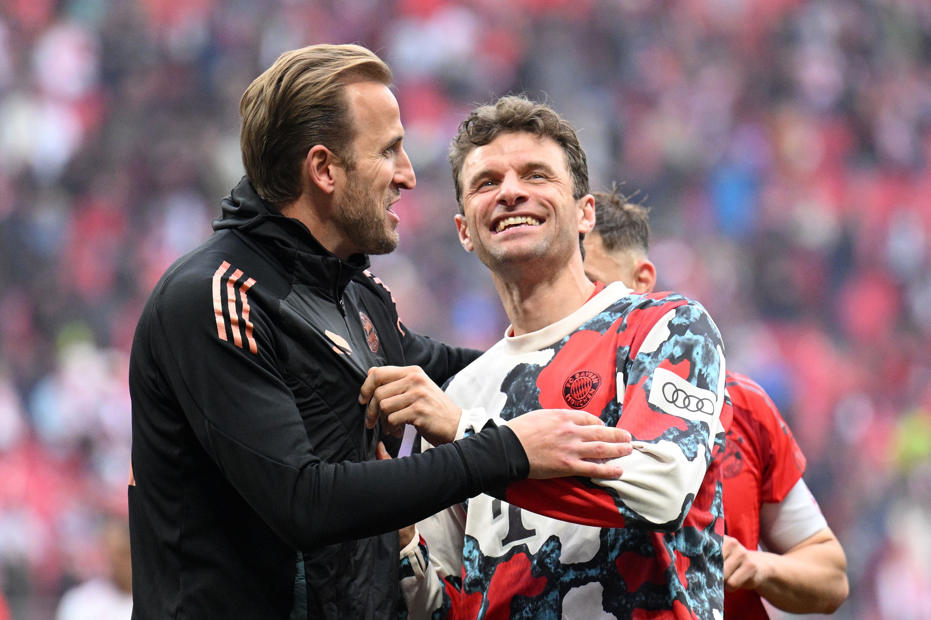 Harry Kane und Thomas Müller lachen und umarmen sich nach einem Fußballspiel.
