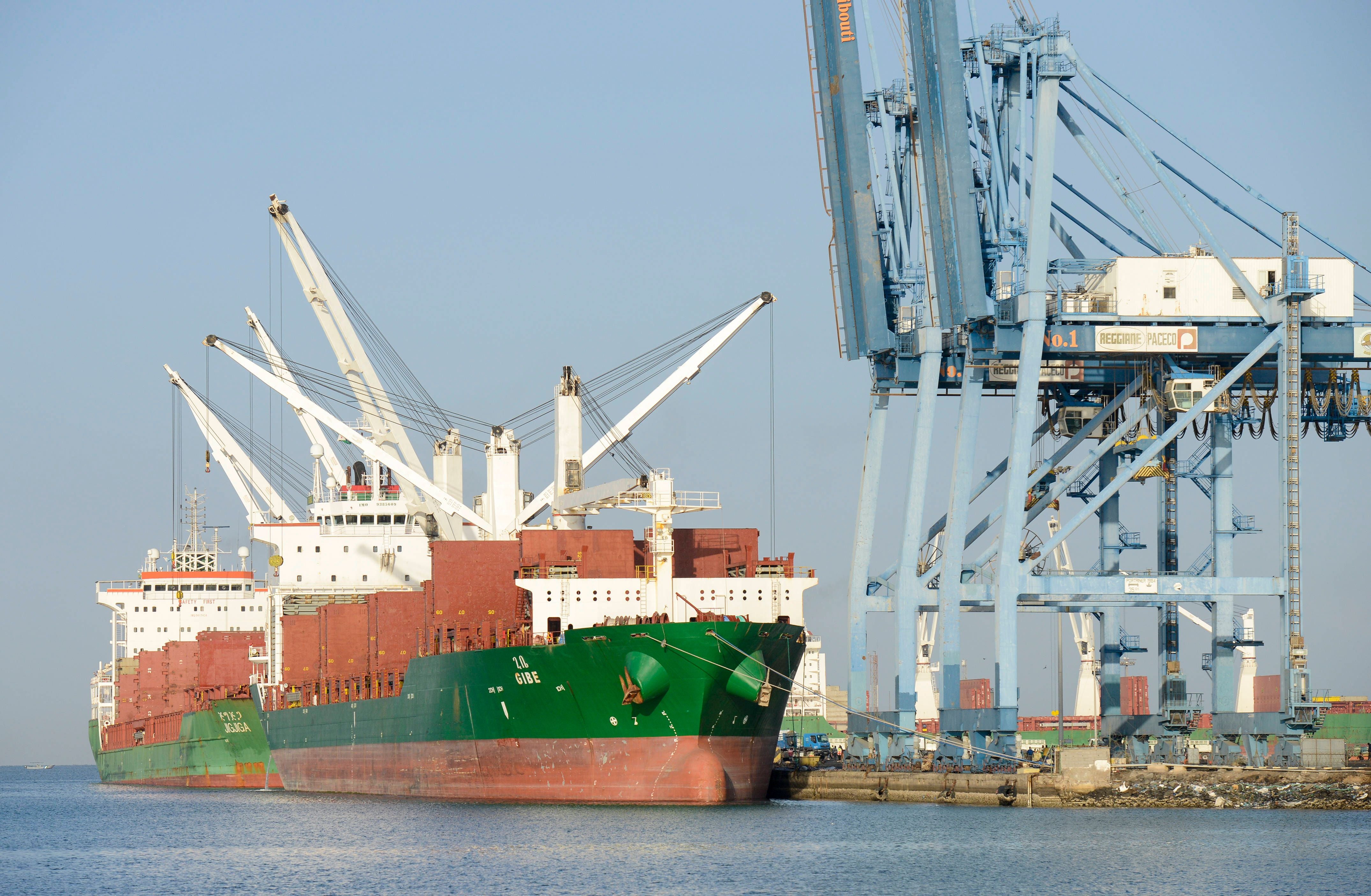 Zwei Frachtschiffe liegen im Hafen von Dschibuti neben großen blauen Verladekränen.