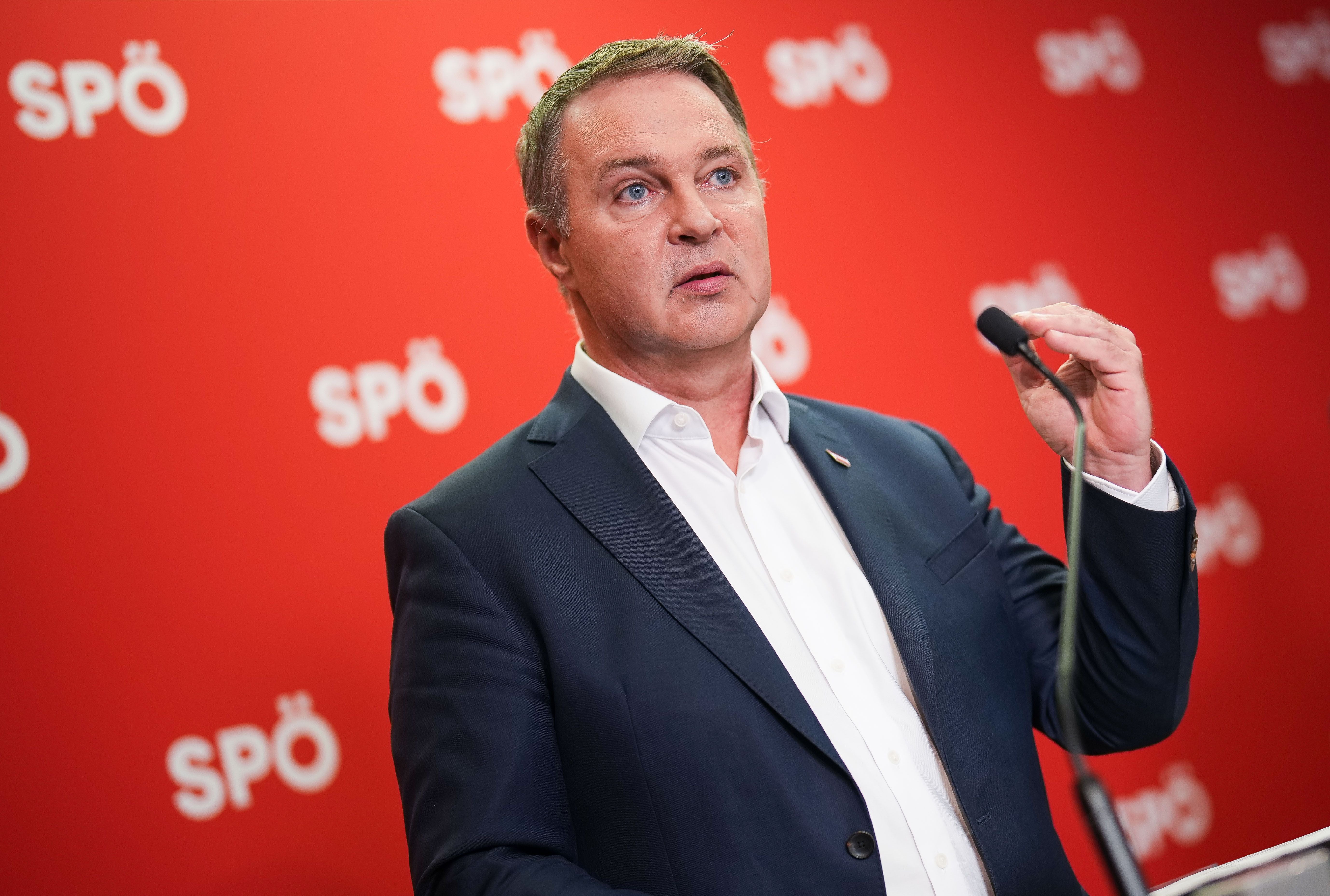 Ein Mann im Anzug spricht am Rednerpult vor rotem Hintergrund mit SPÖ-Logos.