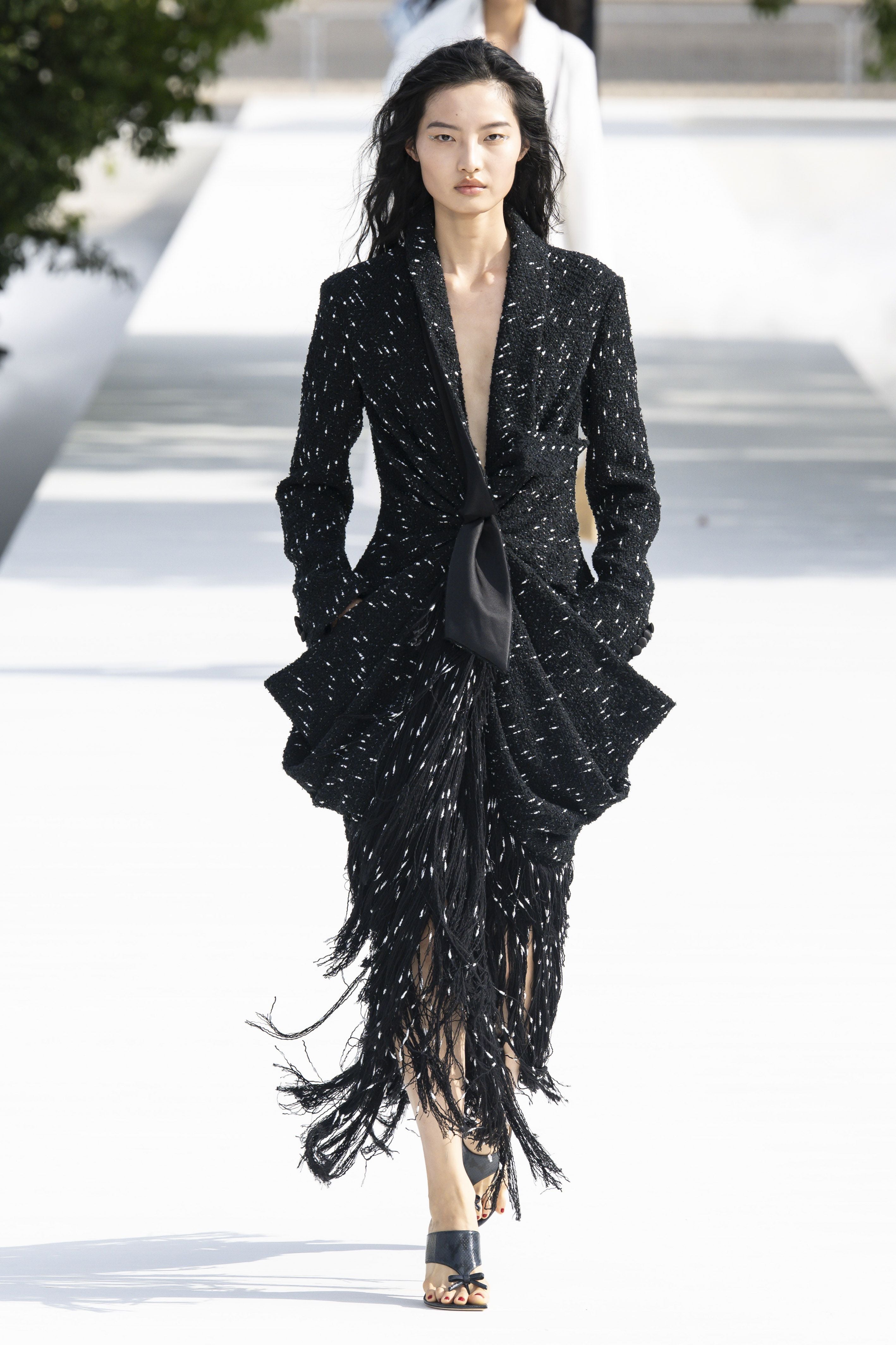 Model in schwarzem Fransen-Kleid läuft über den Laufsteg bei einer Modenschau in Paris.