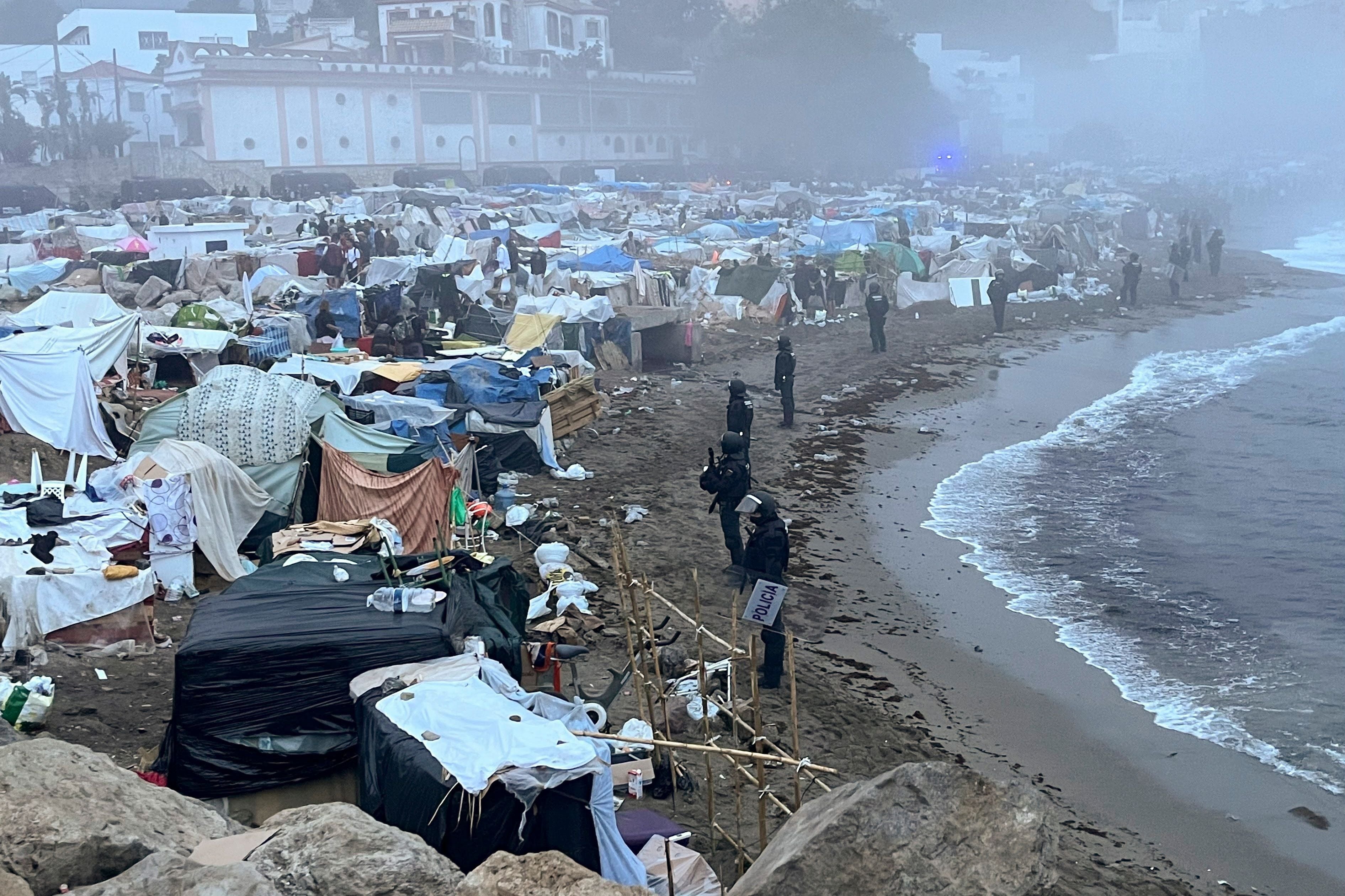 Polizisten räumen ein großes Migrantencamp am Strand von Ceuta bei dichtem Nebel.