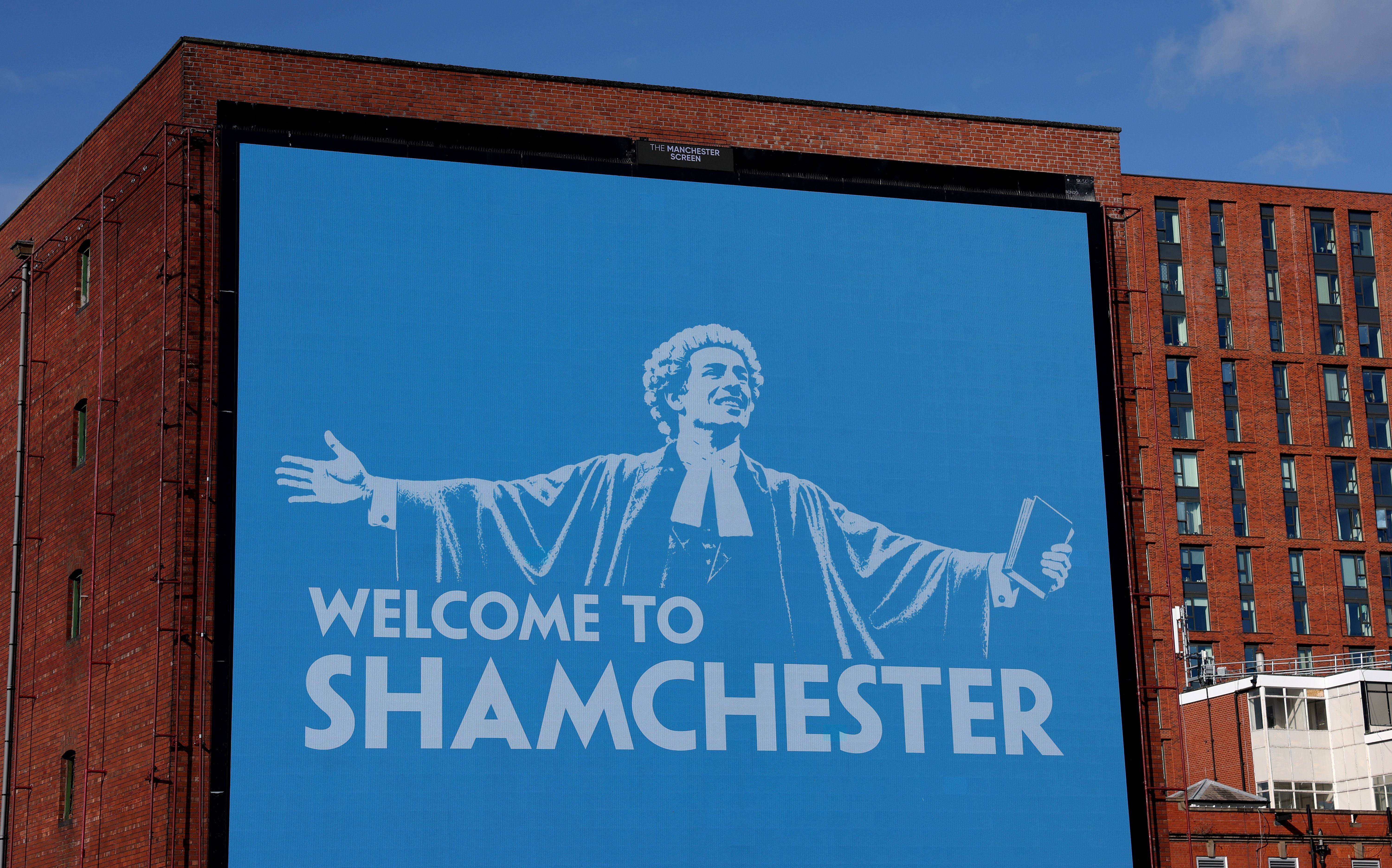Großes Plakat in Manchester mit der Aufschrift "WELCOME TO SHAMCHESTER" und einer Richterfigur.