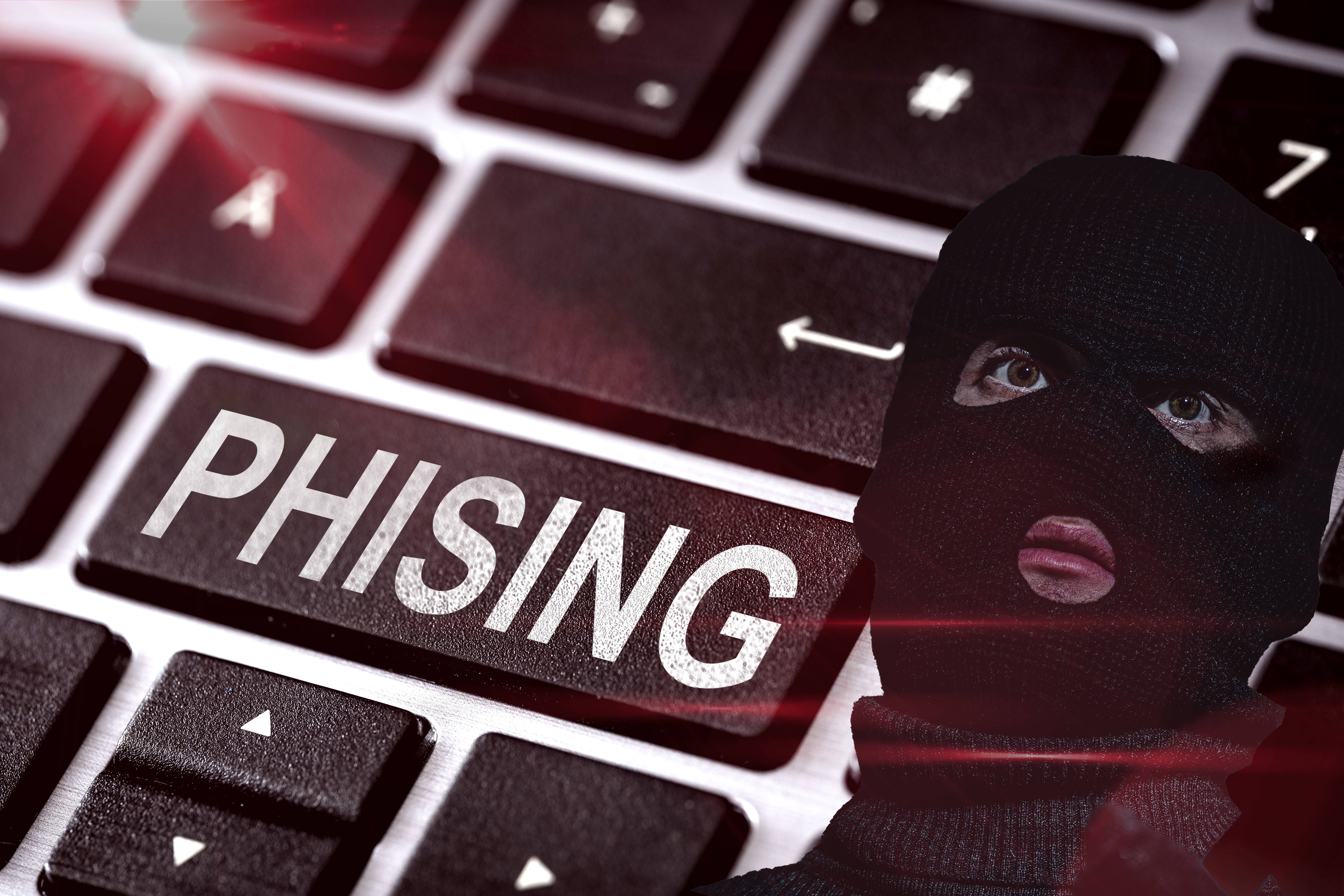 Tastatur mit "PHISHING"-Taste neben Person mit schwarzer Maske, Symbol für Internetbetrug.