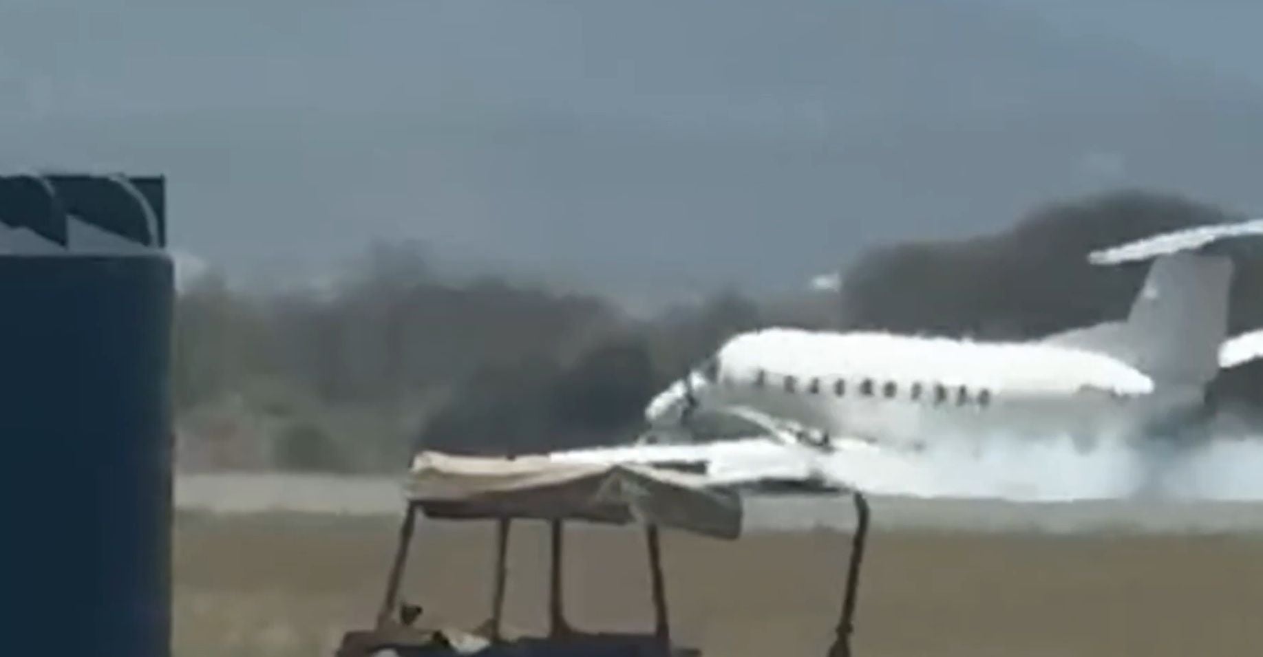 Ein weißes Flugzeug raucht bei einer Notlandung auf einer Landebahn im Freien.