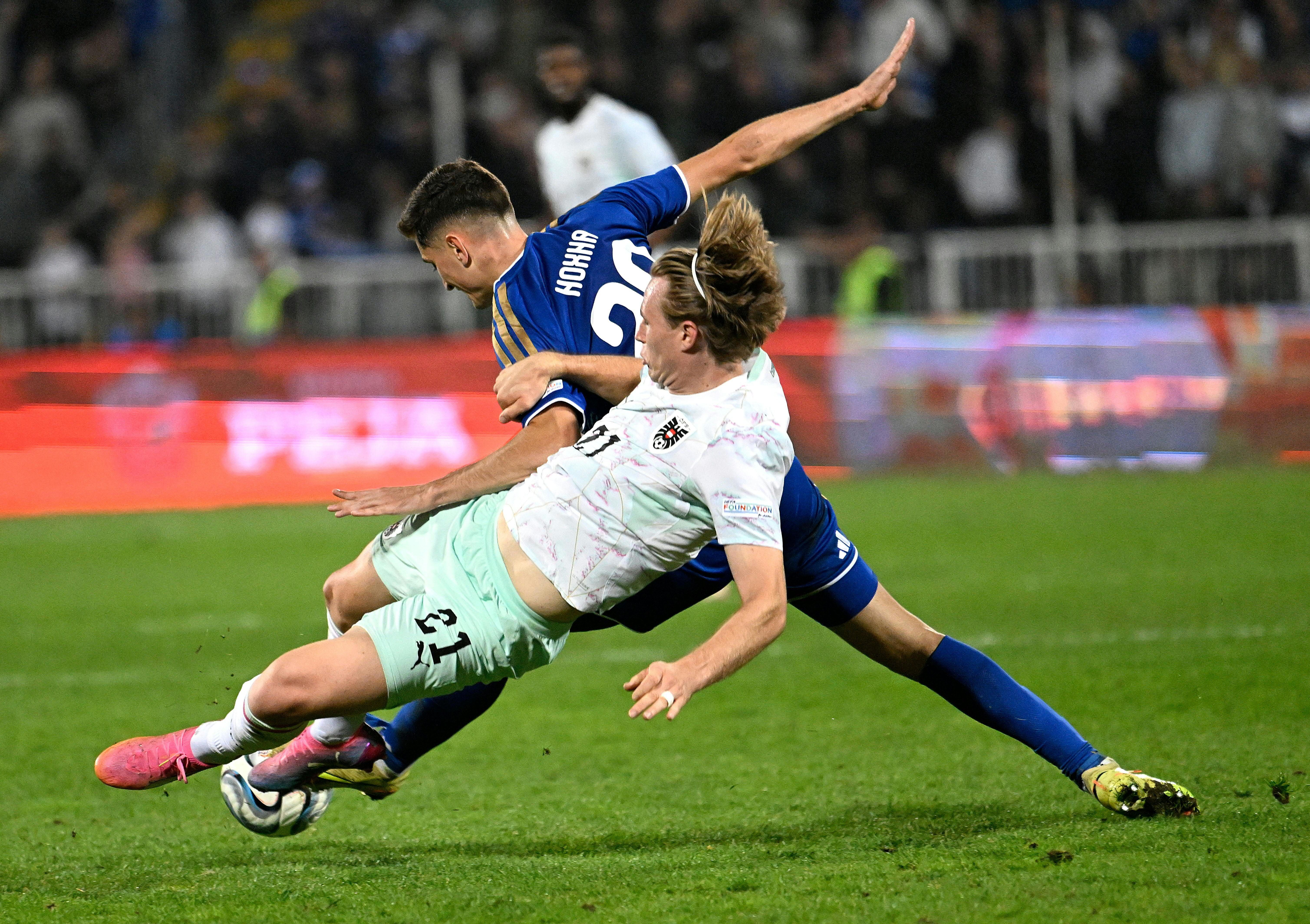 Zwei Fußballspieler ringen während eines Spiels um den Ball und fallen zu Boden.