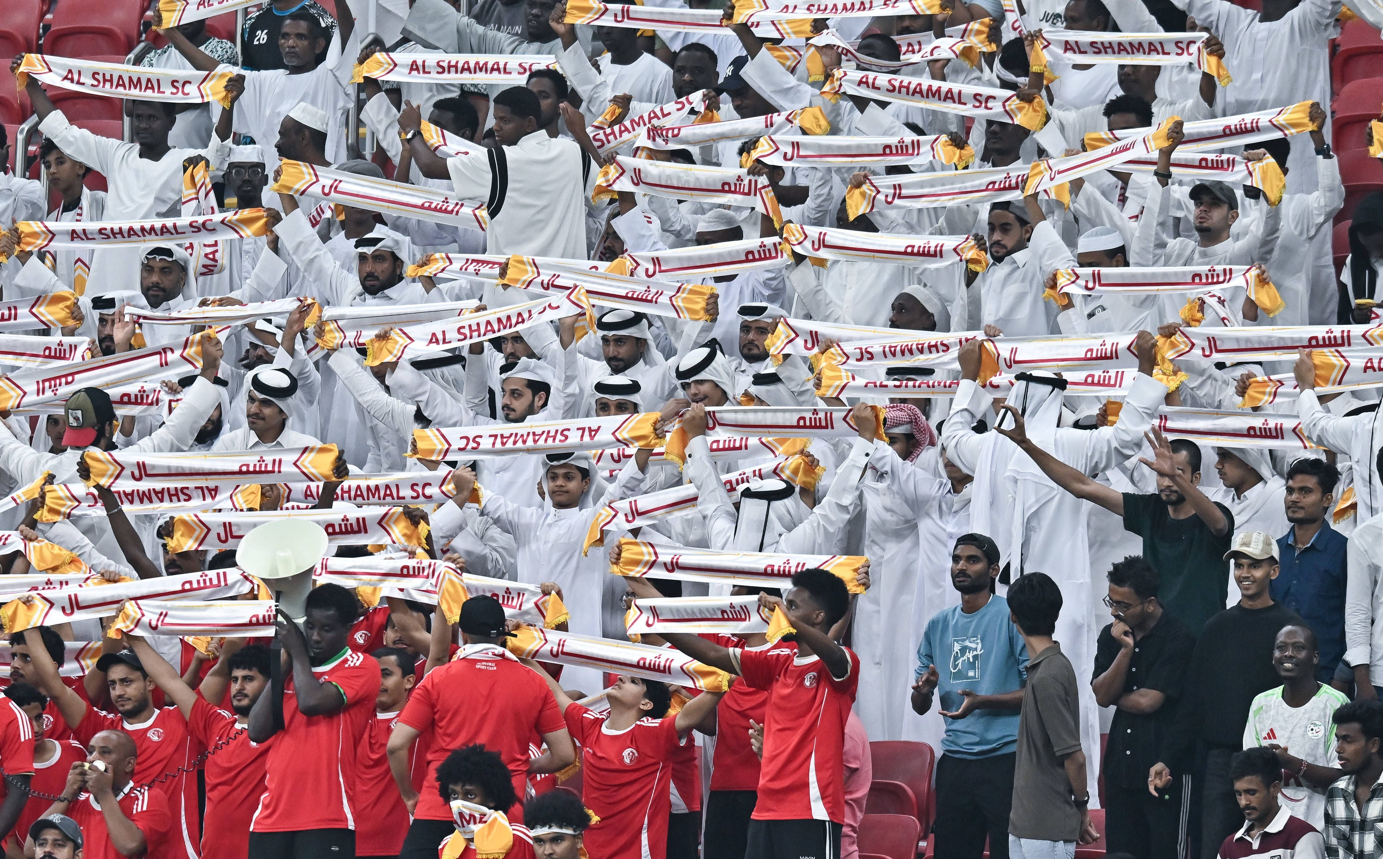 Al Shamal SC-Fans jubeln im Stadion mit Schals während eines Fußballspiels in Katar.