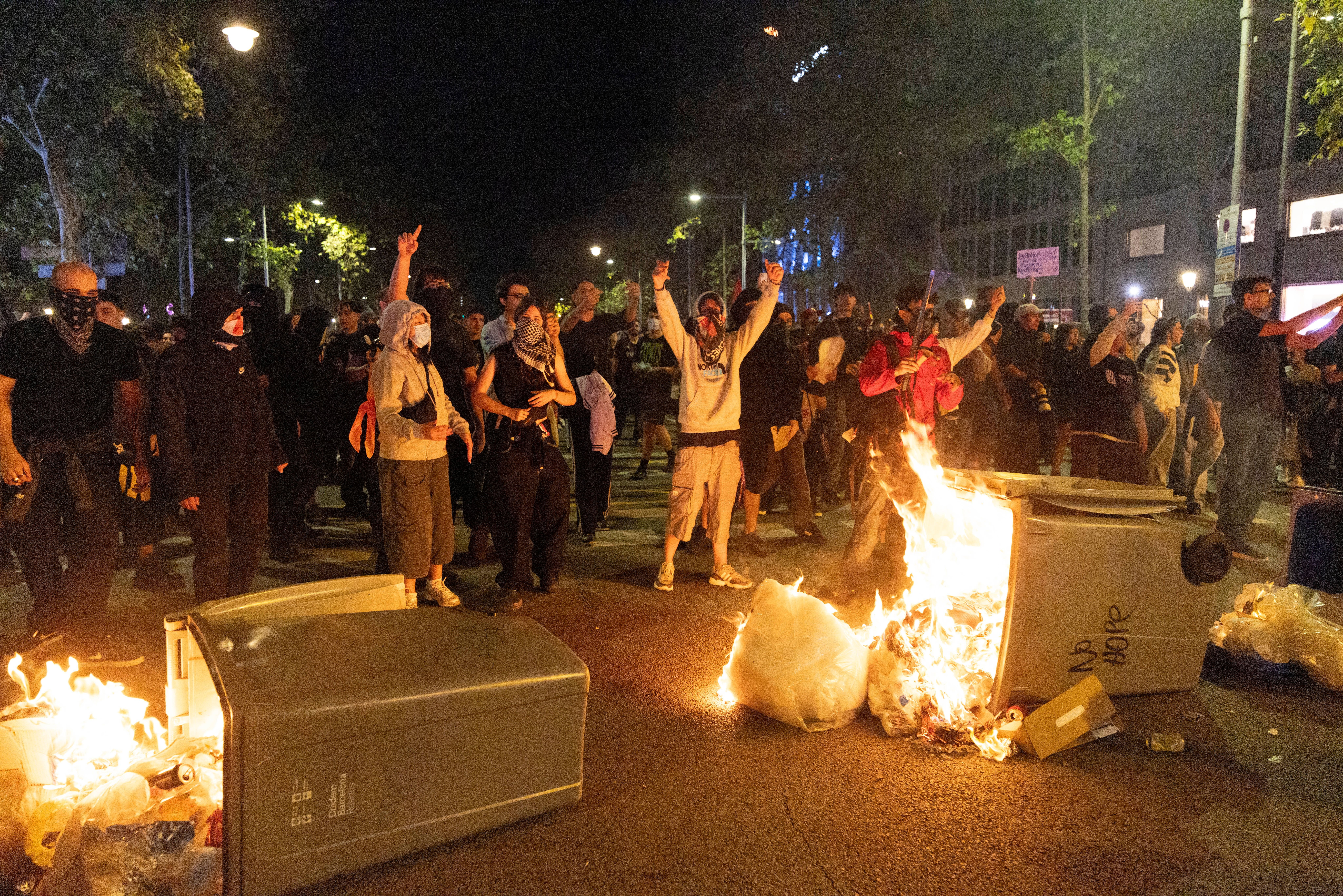 Menschen protestieren nachts in Barcelona, Müllcontainer brennen auf der Straße.