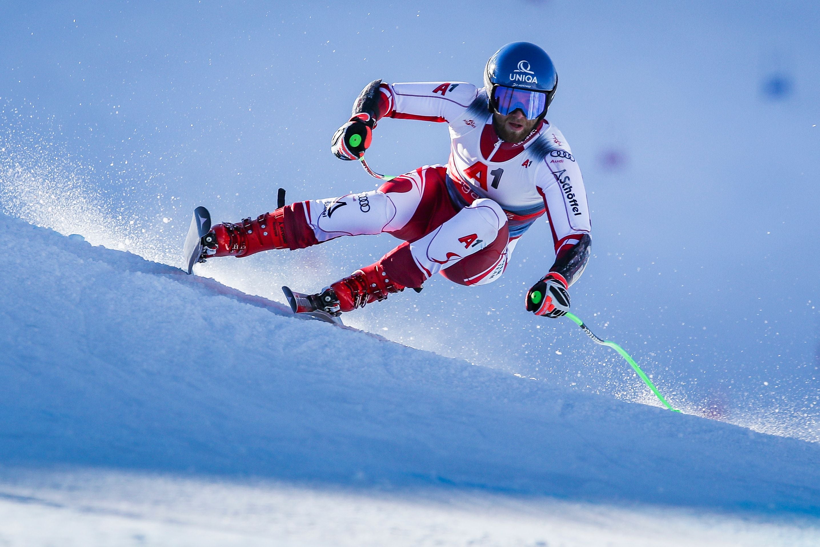 Ein Skirennläufer fährt in rasanter Kurve eine verschneite Piste hinunter.
