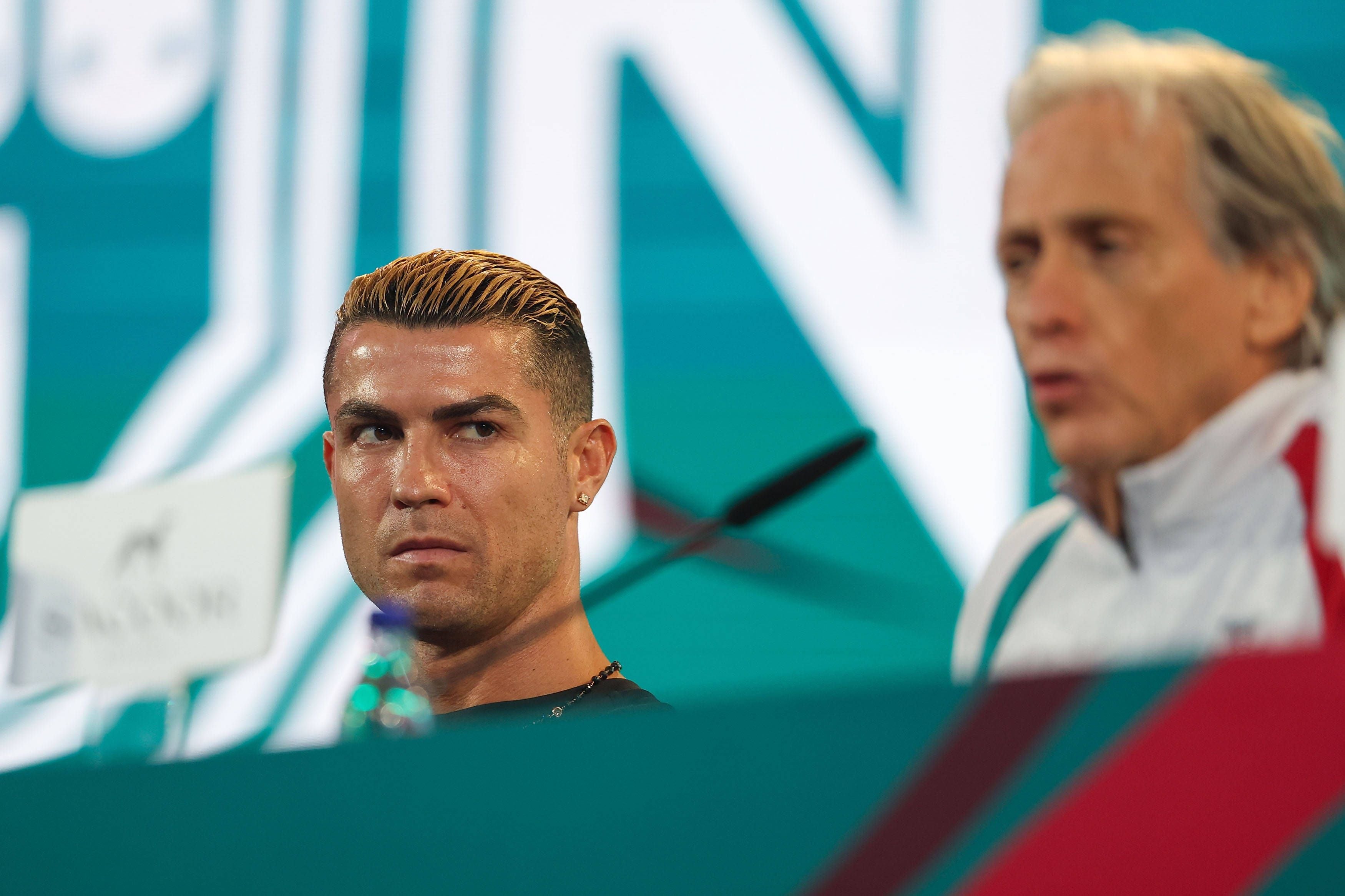 Cristiano Ronaldo blickt auf einer Pressekonferenz skeptisch zur Seite, während neben ihm Trainer Jorge Jesus zu sehen ist.