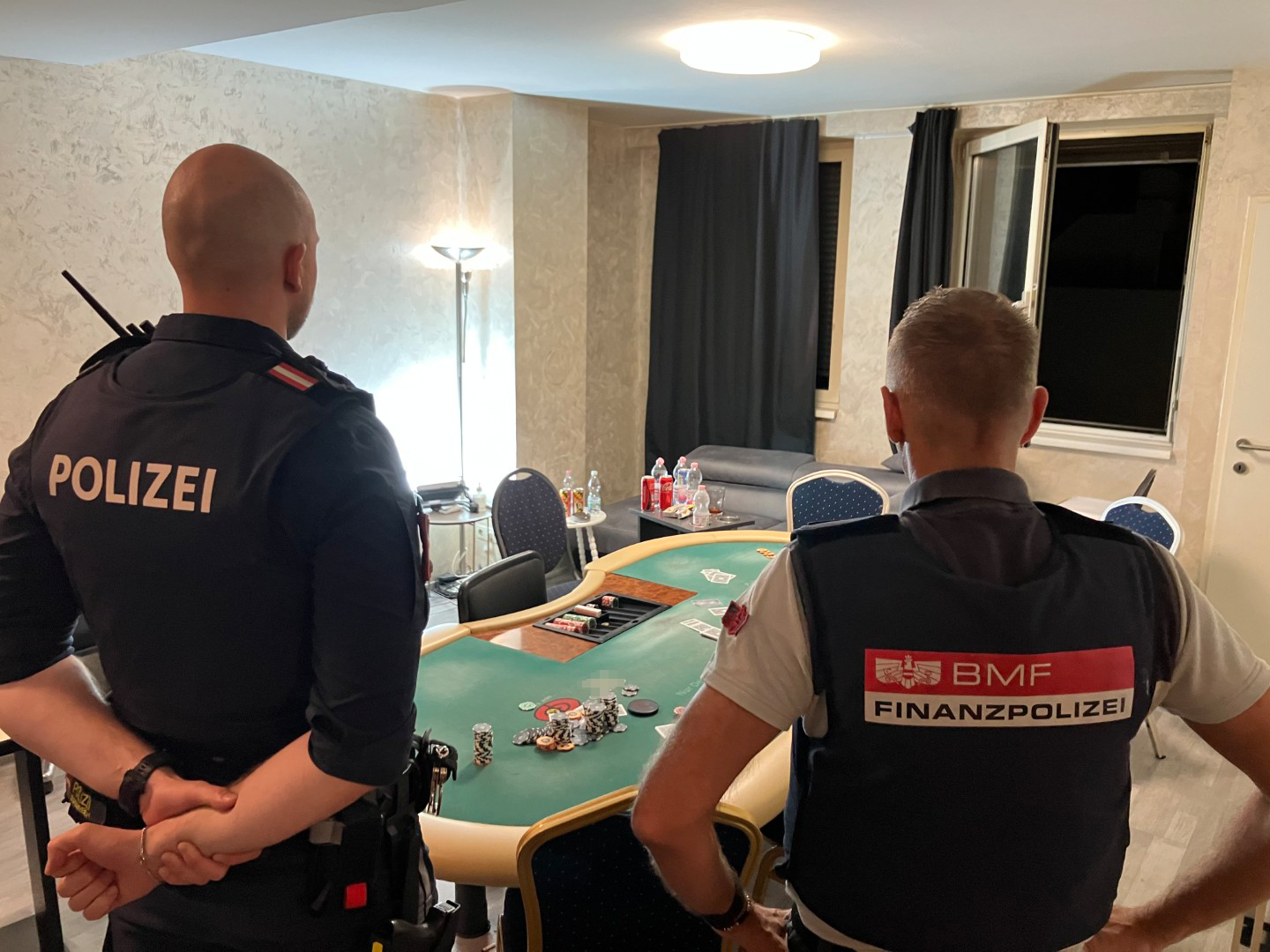 Zwei Polizisten stehen an einem Pokertisch in einem Raum mit Spielchips und Getränken.