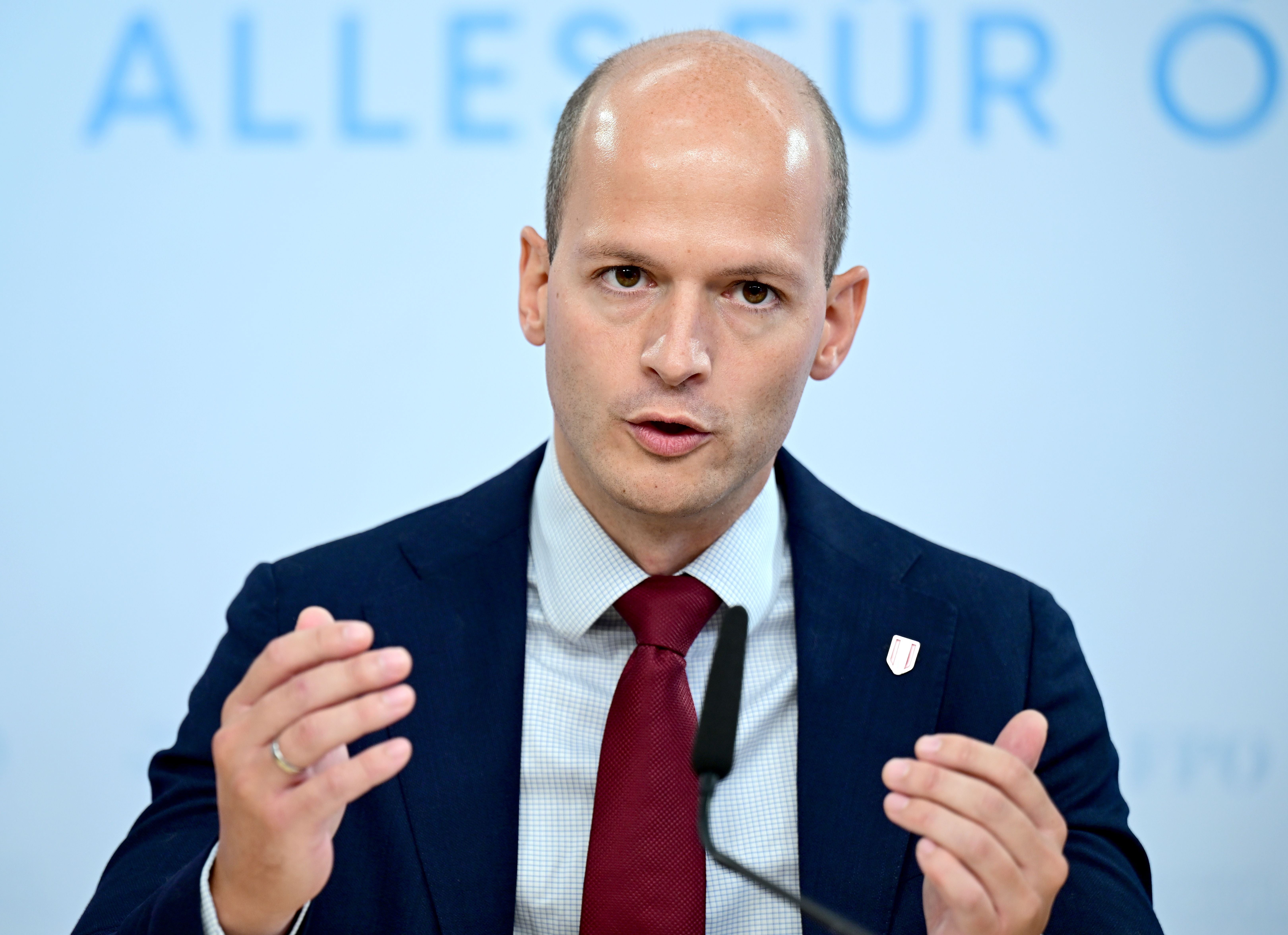 Ein Mann im Anzug spricht auf einer Pressekonferenz und gestikuliert mit den Händen.
